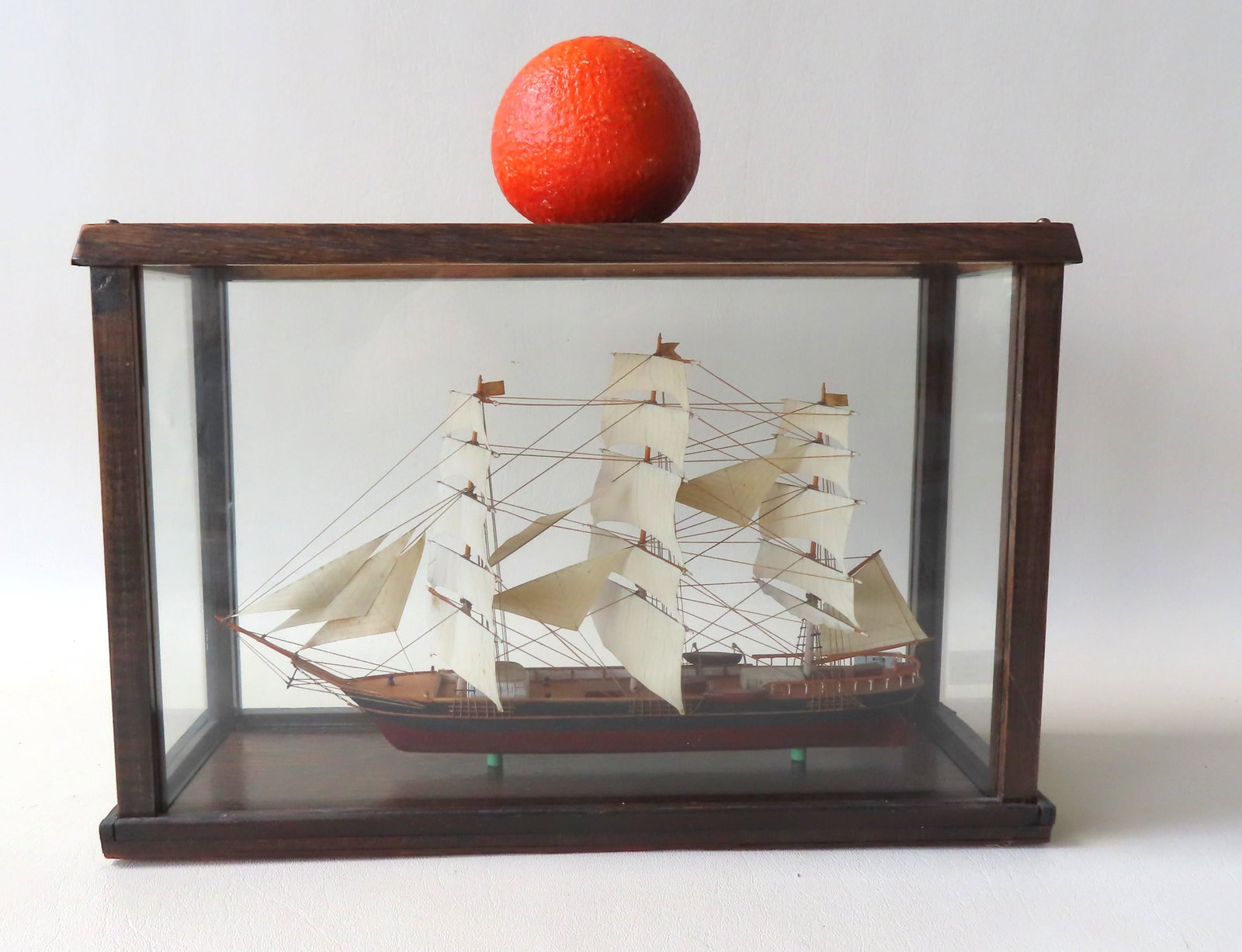 Wooden model of a barque sailing vessel, complete with: Wooden model of a barque sailing vessel, complete with rigging and lifeboats, mounted within a glass display case with wood frame.. Probably early 20th century. The case is later 20th century. Both in