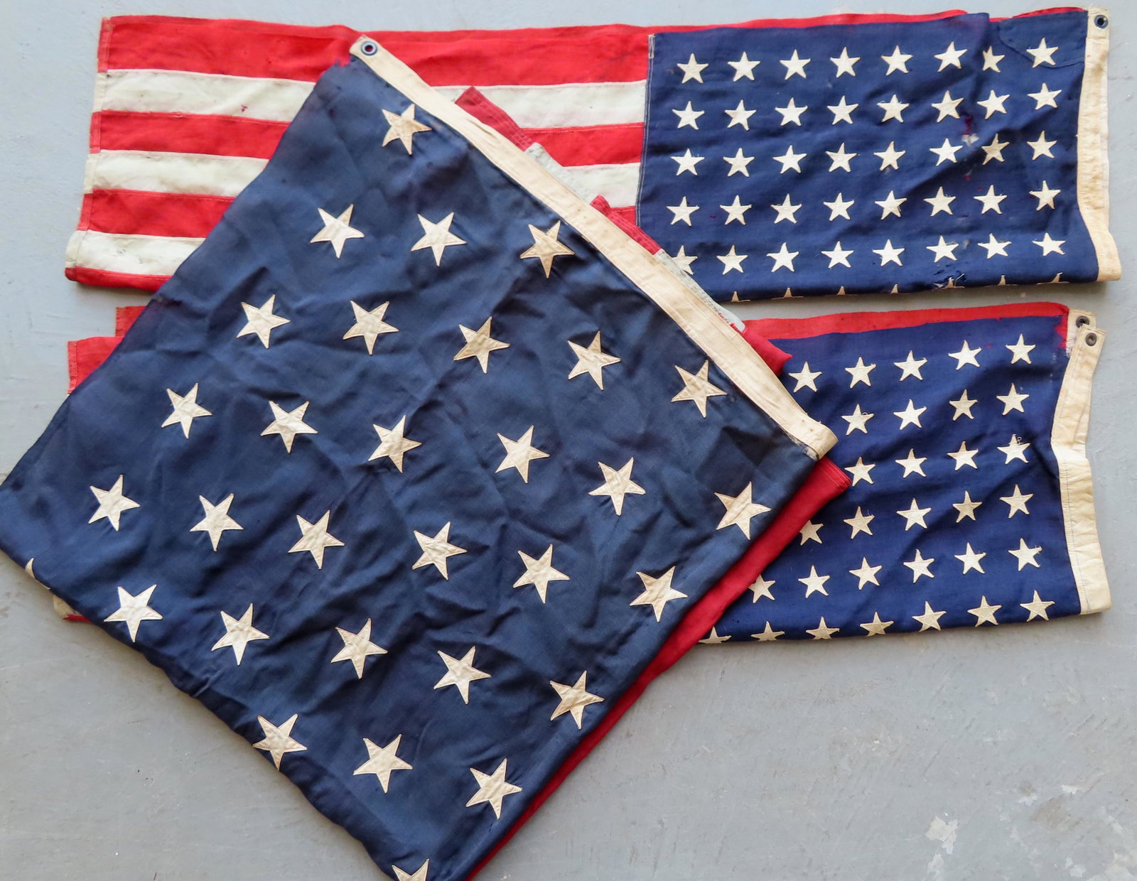 Three American flags including: Two small flags with 48: Three American flags including: Two small flags with 48 stars, each with some moth damage (see photos); and a large 45 star flag, minor small holes, and overall good condition - measures 6' x 12'.