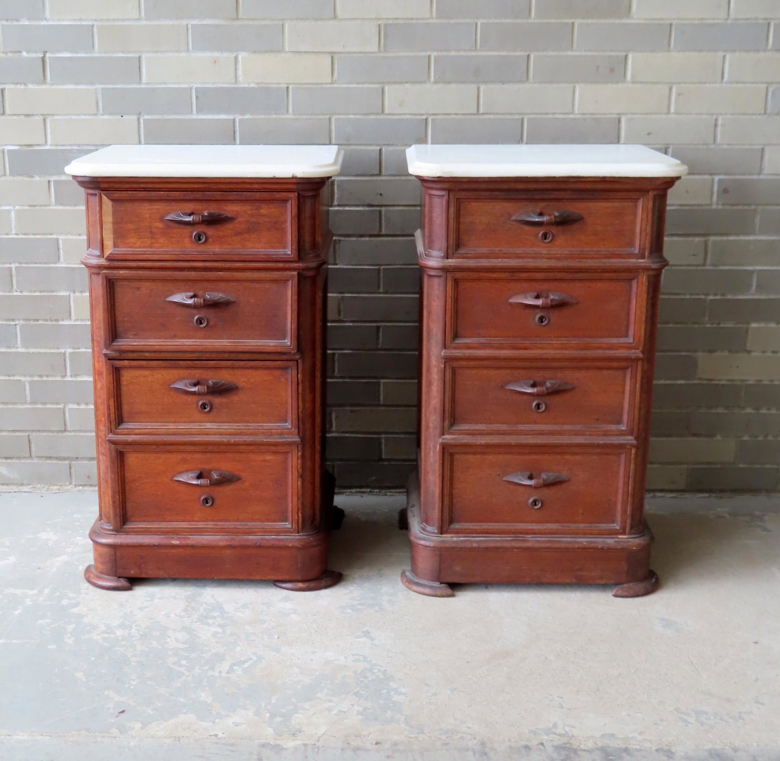 Two Victorian black walnut 4 drawer stands with carved: Two Victorian black walnut 4 drawer stands with carved wooden pulls. Each stand with white marble tops with molded edges and the drawers all with locking mechanisms but no key. Missing backboards, sli