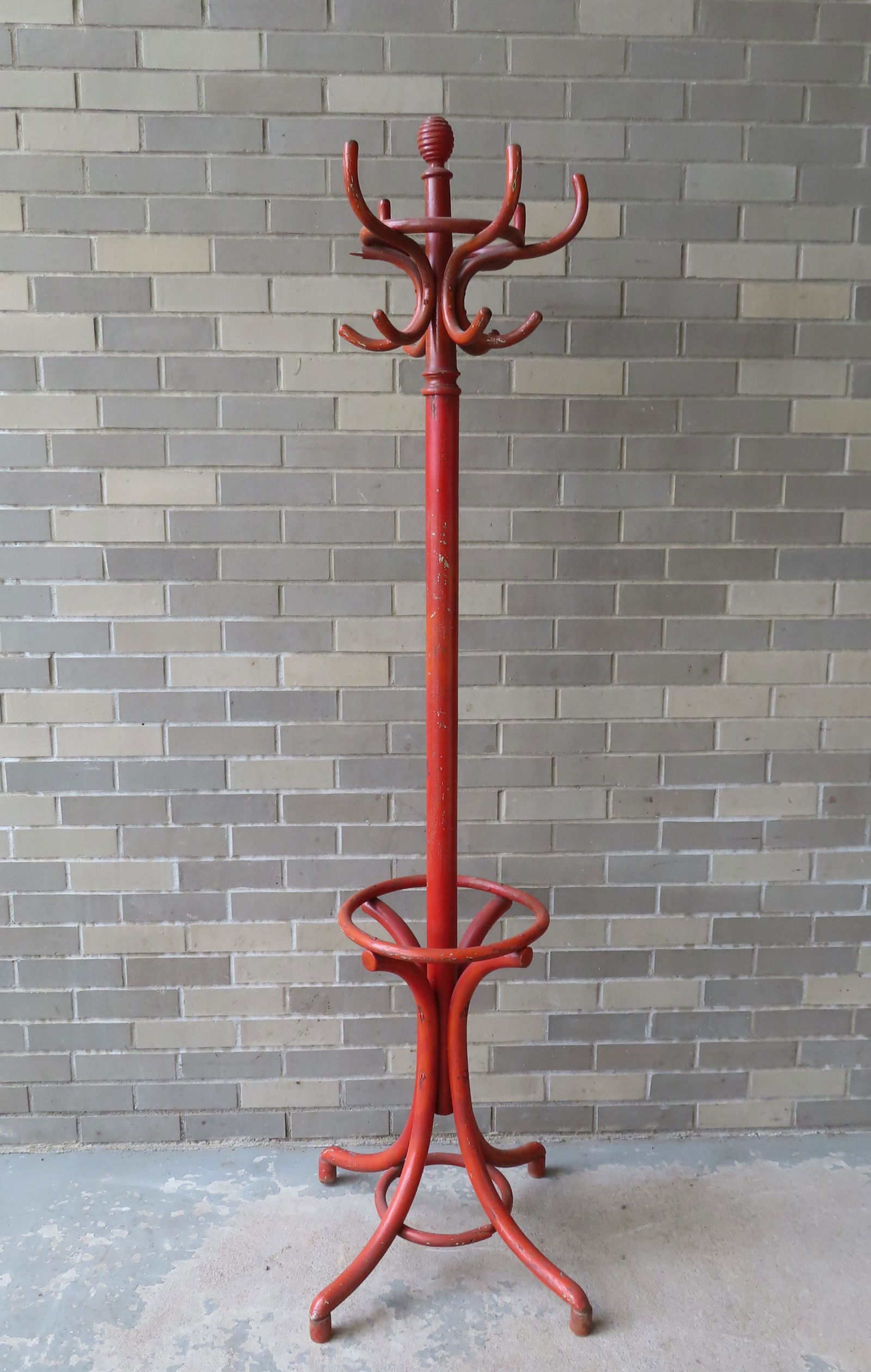 A floor standing bentwood coat and hat rack in old: A floor standing bentwood coat and hat rack in old orange/red paint, early 20th century; Some paint crazing and loss to 1/2 of one hat hook, else good condition. Measures 73 3/4"H x 24 1/2"W (at base)