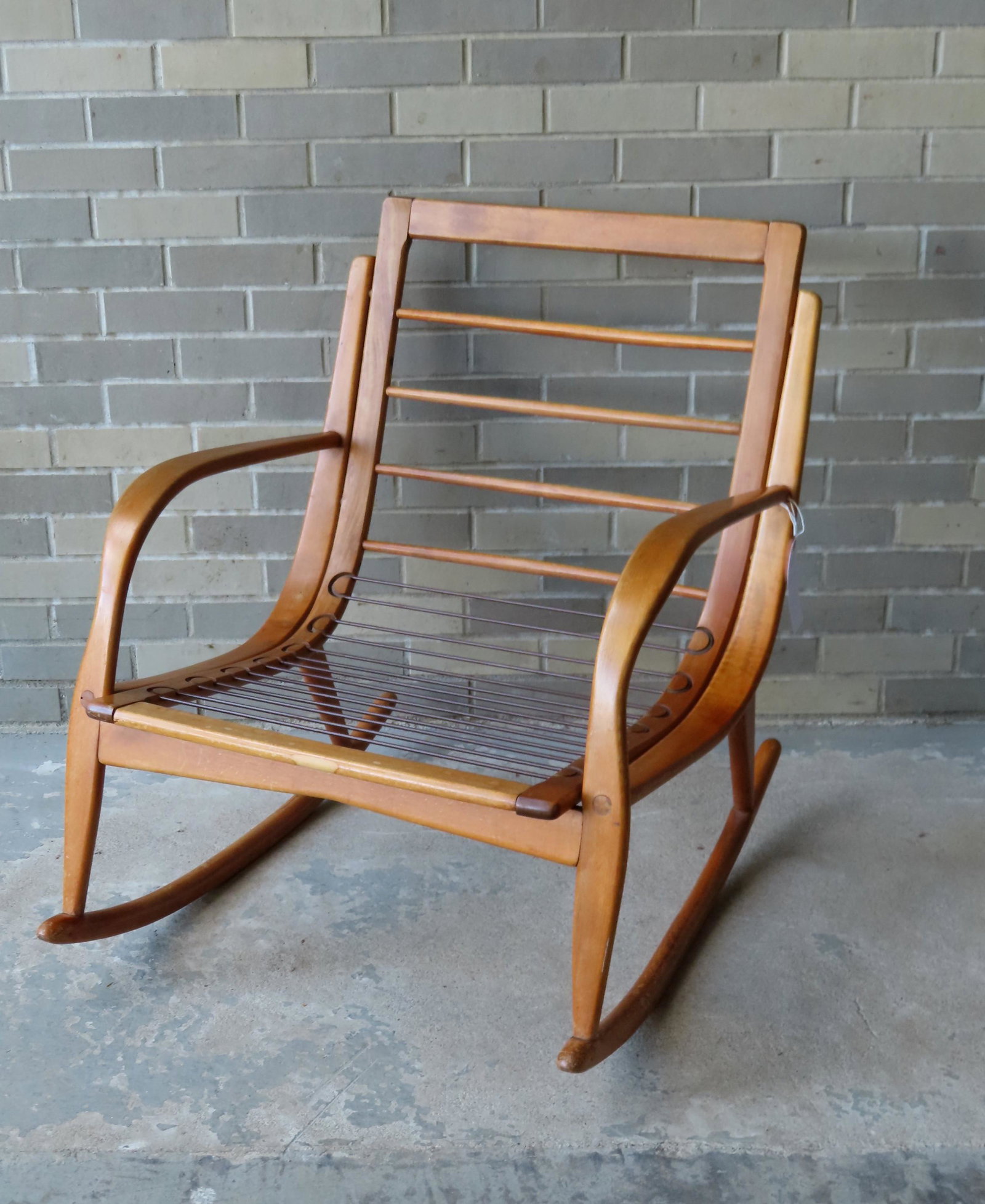 A Danish modern style wooden rocker that is a maple: A Danish modern style wooden rocker that is a maple color, possibly light teakwood, with original supporting seat straps still intact, but missing cushion - light staining, otherwise good condition. M