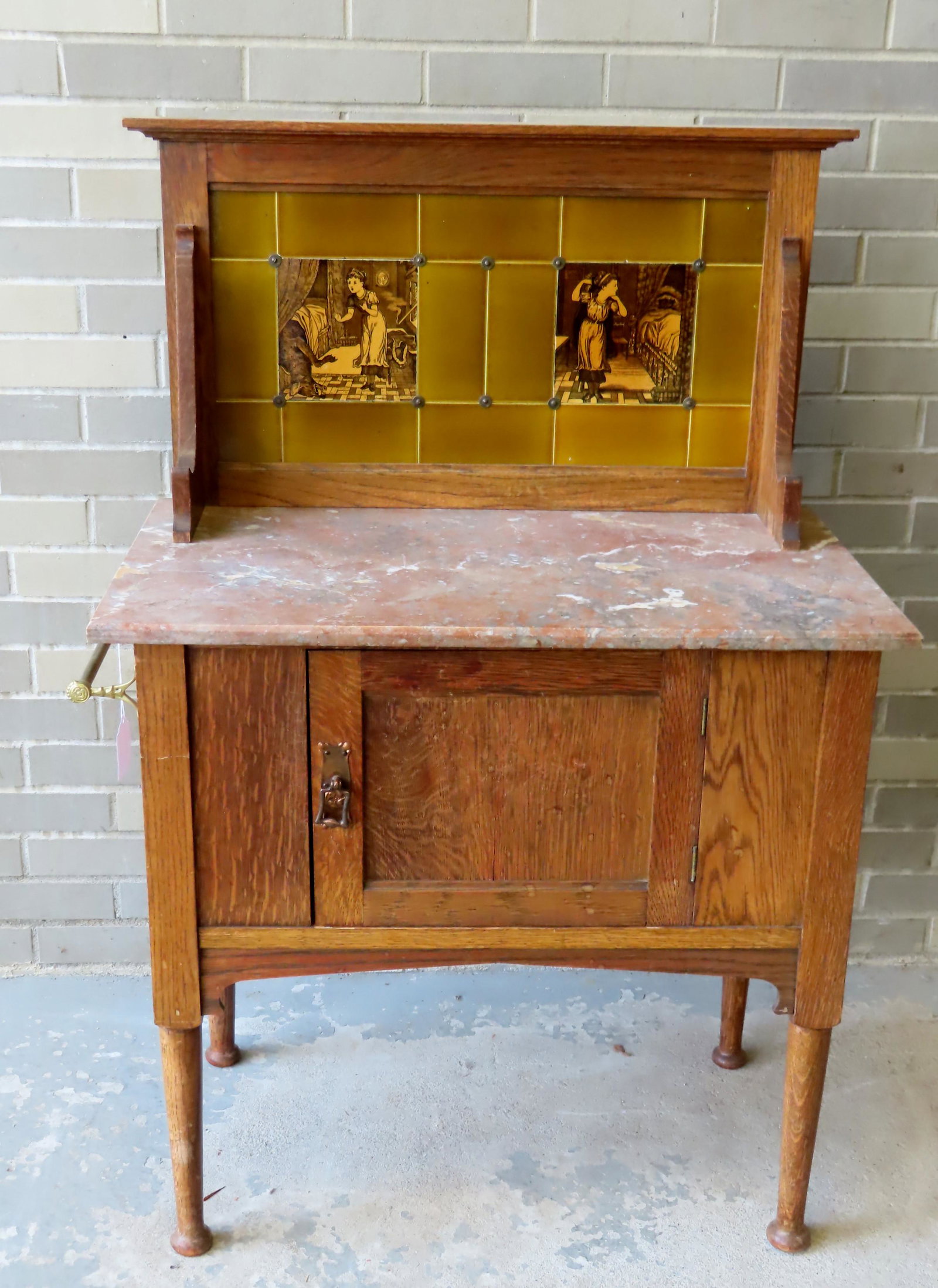 An English marble top washstand with tiled back: An English marble top washstand with tiled back decorated with 2 tiles of Little Red Riding Hood and the Big Bad Wolf (in her bed). The gray marble top over a single door. Measures 30"W x 18"D x 45 3/