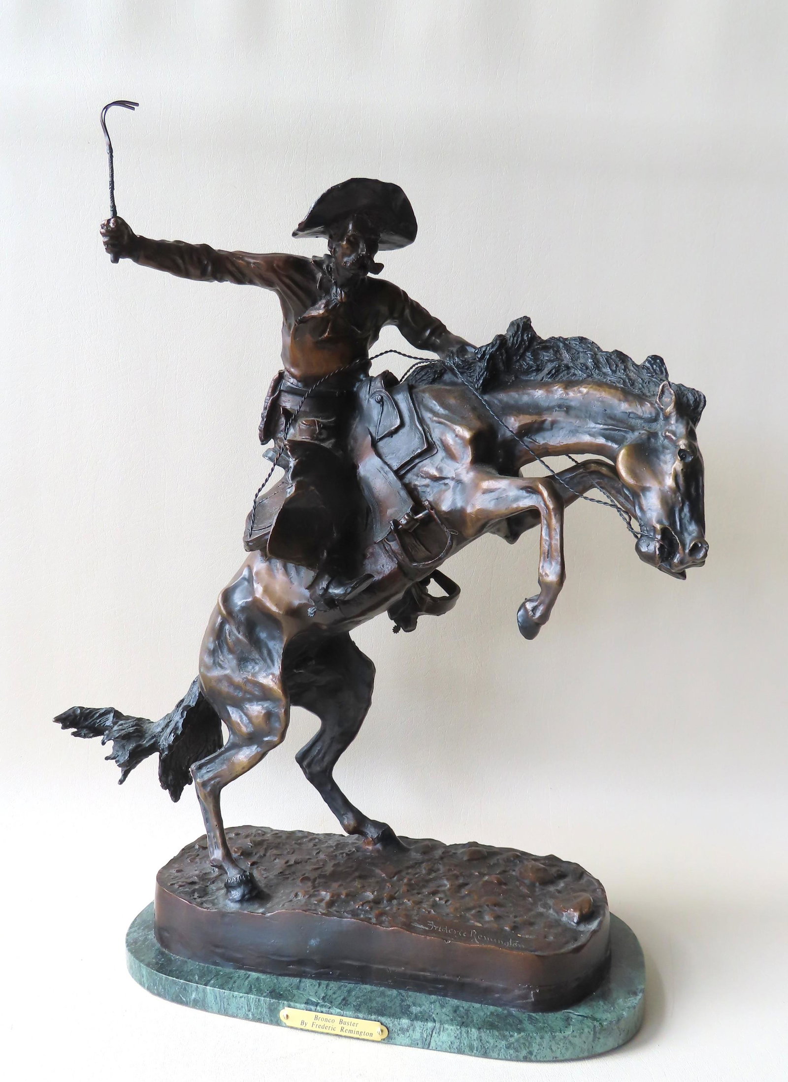 A large bronze sculpture after Frederic Remington: A large bronze sculpture after Frederic Remington mounted on a marble base and showing very detailed work and excellent patination . The brass plaque applied to base reads "Bronco Buster by Frederic R