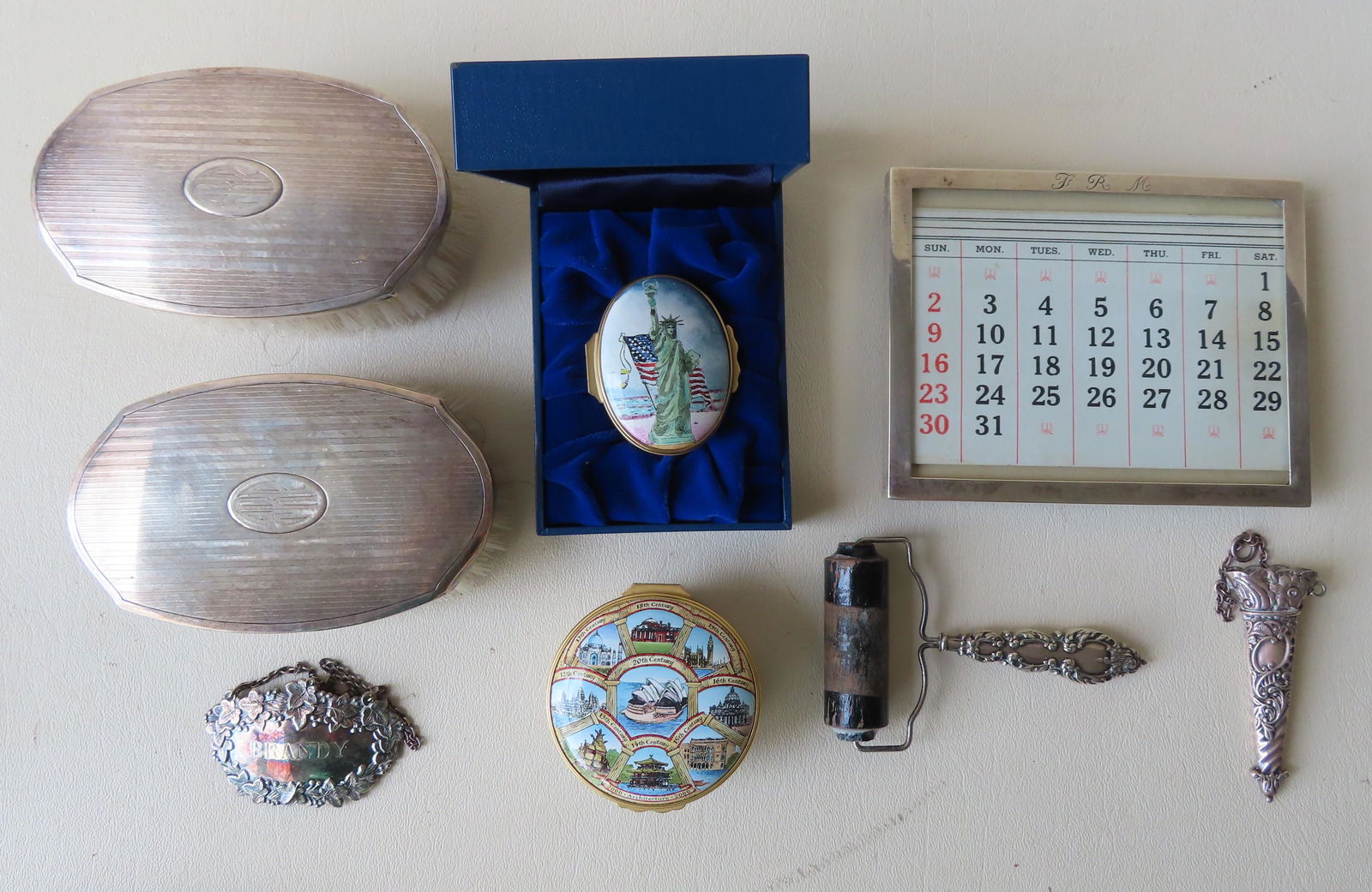 A grouping of decorative objects including: Liquor: A grouping of decorative objects including: Liquor bottle sterling tag marked "Brandy"; sterling silver picture frame - opening 5" x 3 7/8"; an ornate miniature sterling scabbard (?) - 2 7/8"L; an ink