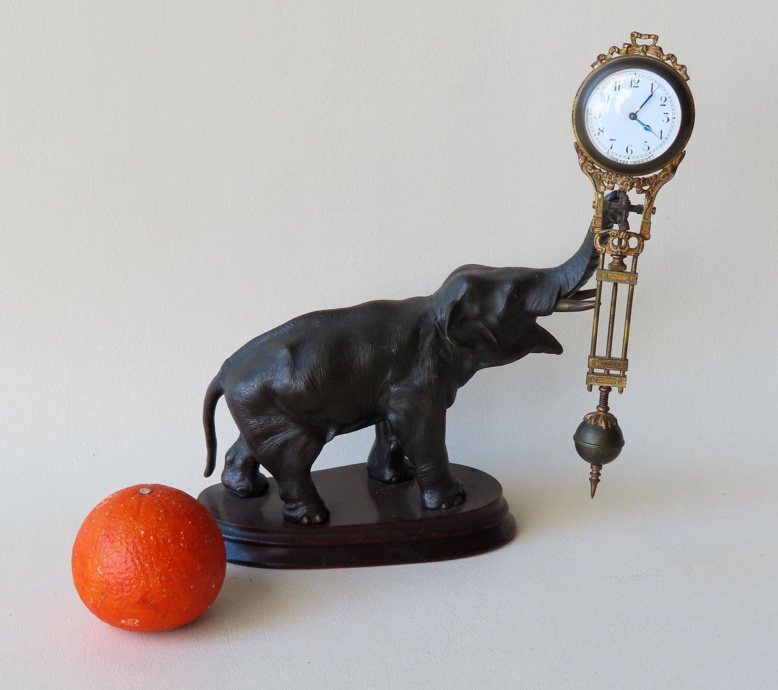 Junghans elephant swinger clock. The metal elephant in: Junghans elephant swinger clock. The metal elephant in original gray paint is attached to a wooden platform. The original brass pendulum is decorated with flowers and scrolls and is signed on the enam