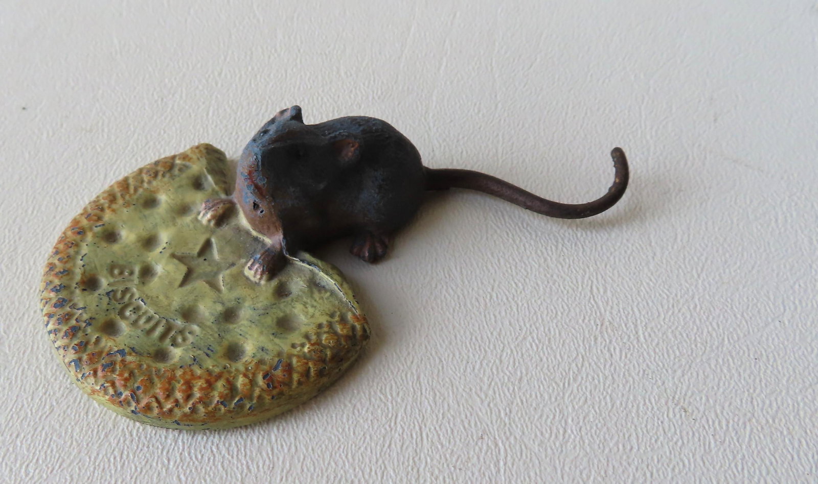 A painted iron (or lead) advertising paperweight: A painted iron (or lead) advertising paperweight depicting a mouse with biscuit. The biscuit with an impressed mark of a star over the word "BISCUITS", probably late 19th to early 20th century. 4"L x 