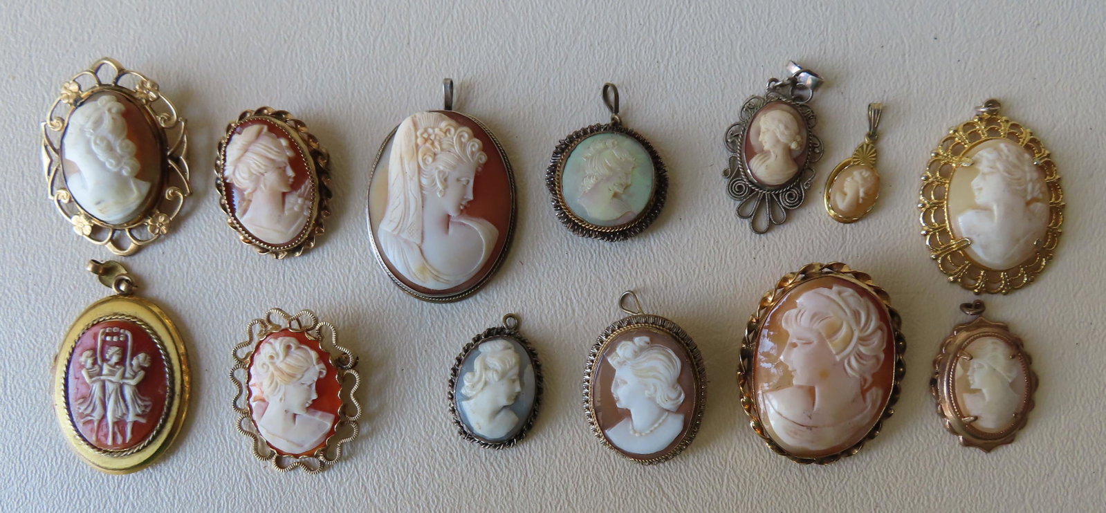 A grouping of 13 cameo pendants and brooches including: A grouping of 13 cameo pendants and brooches including one pendant locket, all in good condition, ranging in size from 3/8" x 3/4" to 1 1/4" x 1 1/2". Probably late 19th to mid 20th century. All appea