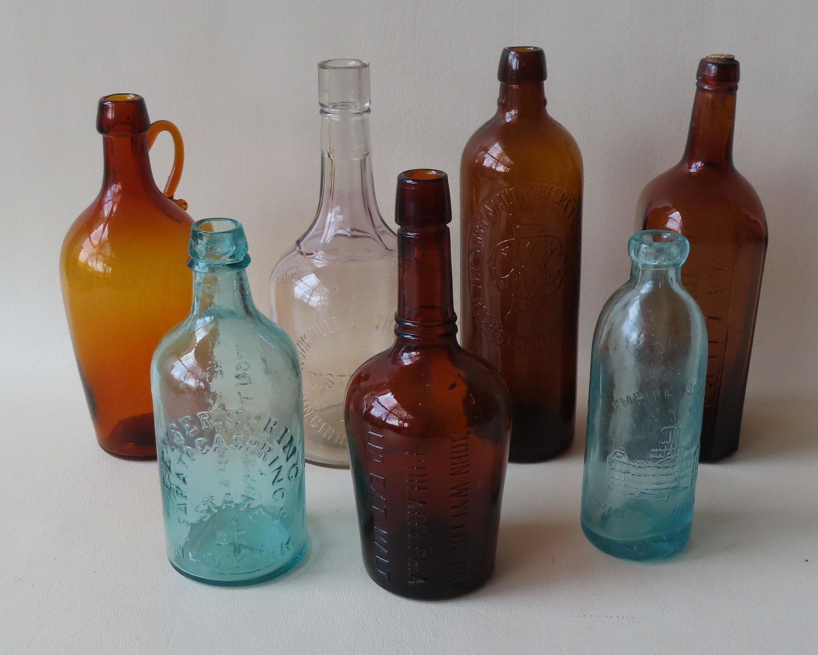 Grouping of 7 vintage bottles including: Aqua colored: Grouping of 7 vintage bottles including: Aqua colored water bottle marked "Hennessy & Nolan Albany N.Y." - and marked on reverse with "Empire State / Trade Mark / Mineral Waters" - 7 1/4"H"; dark ambe