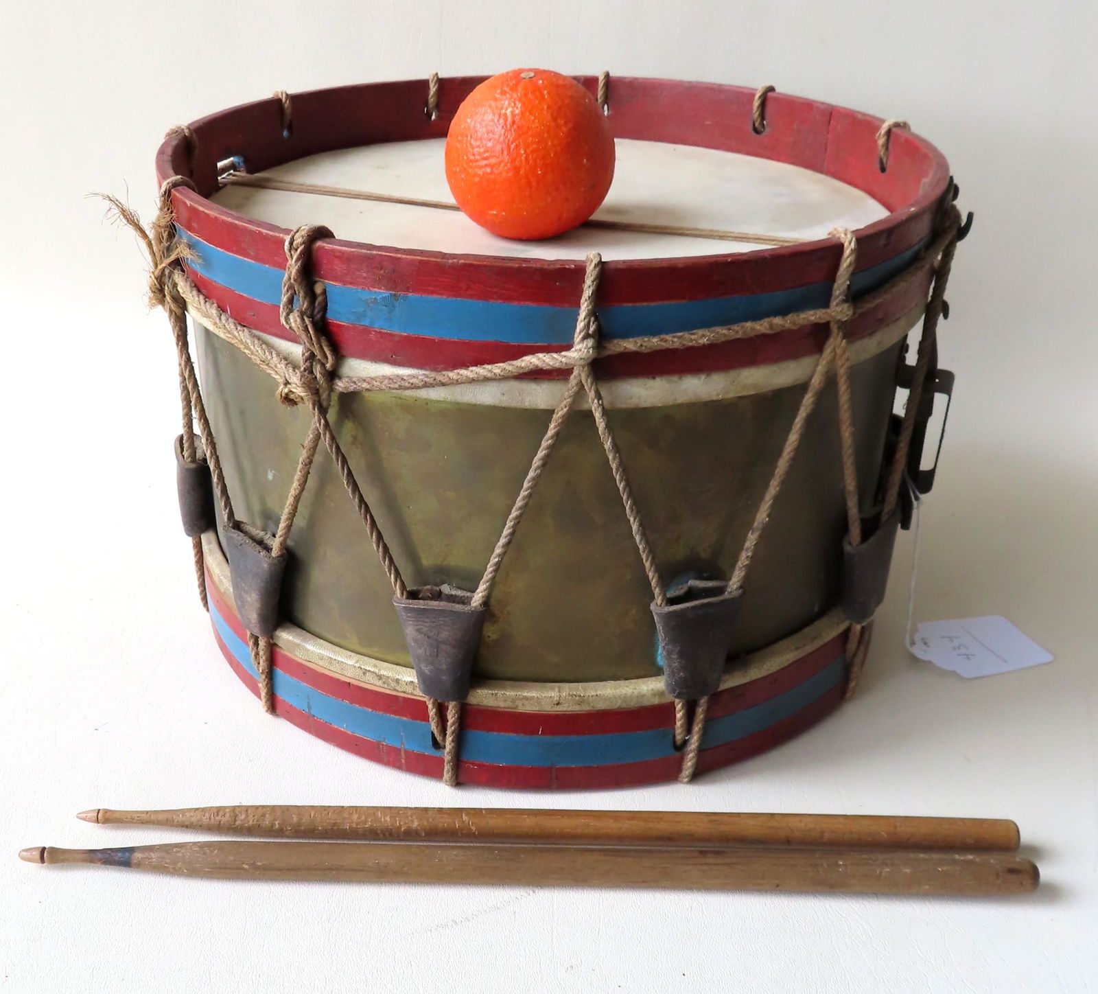 A brass drum with wooden frame in original red, white: A brass drum with wooden frame in original red, white and blue paint, probably French regimental early to mid 20th century. Sold with 2 drumsticks of different sizes. The drum measures 14" diameter x