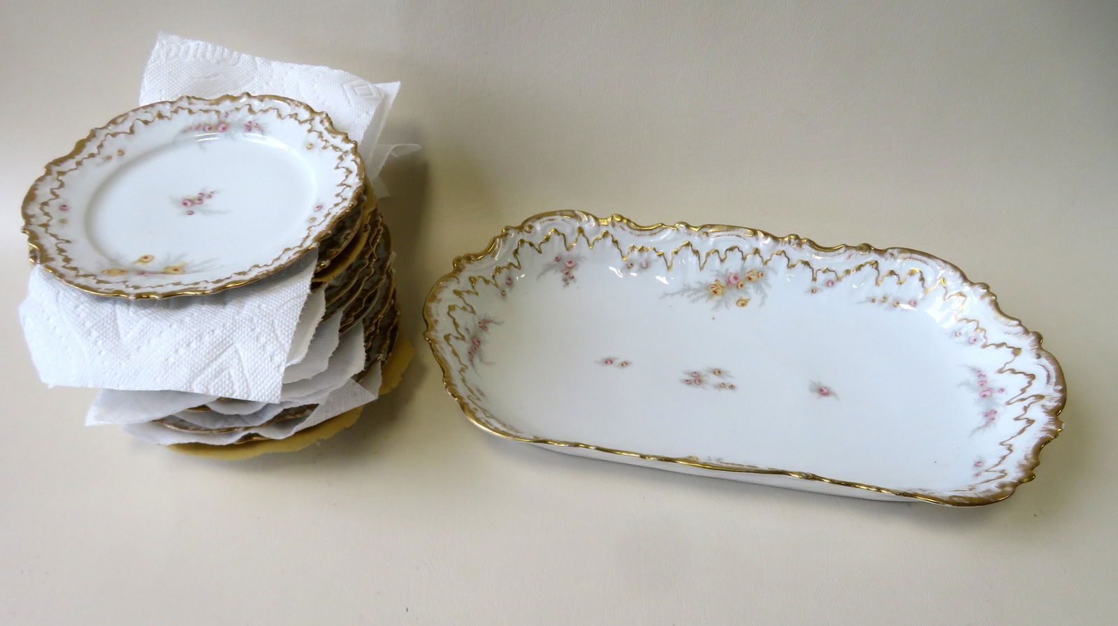 A very fine Limoges fruit or salad porcelain serving: A very fine Limoges fruit or salad porcelain serving set consisting of 12 ornate hand painted floral scalloped edge plates with gold borders, each 7 3/8”Dia., and 1 matching platter that measure
