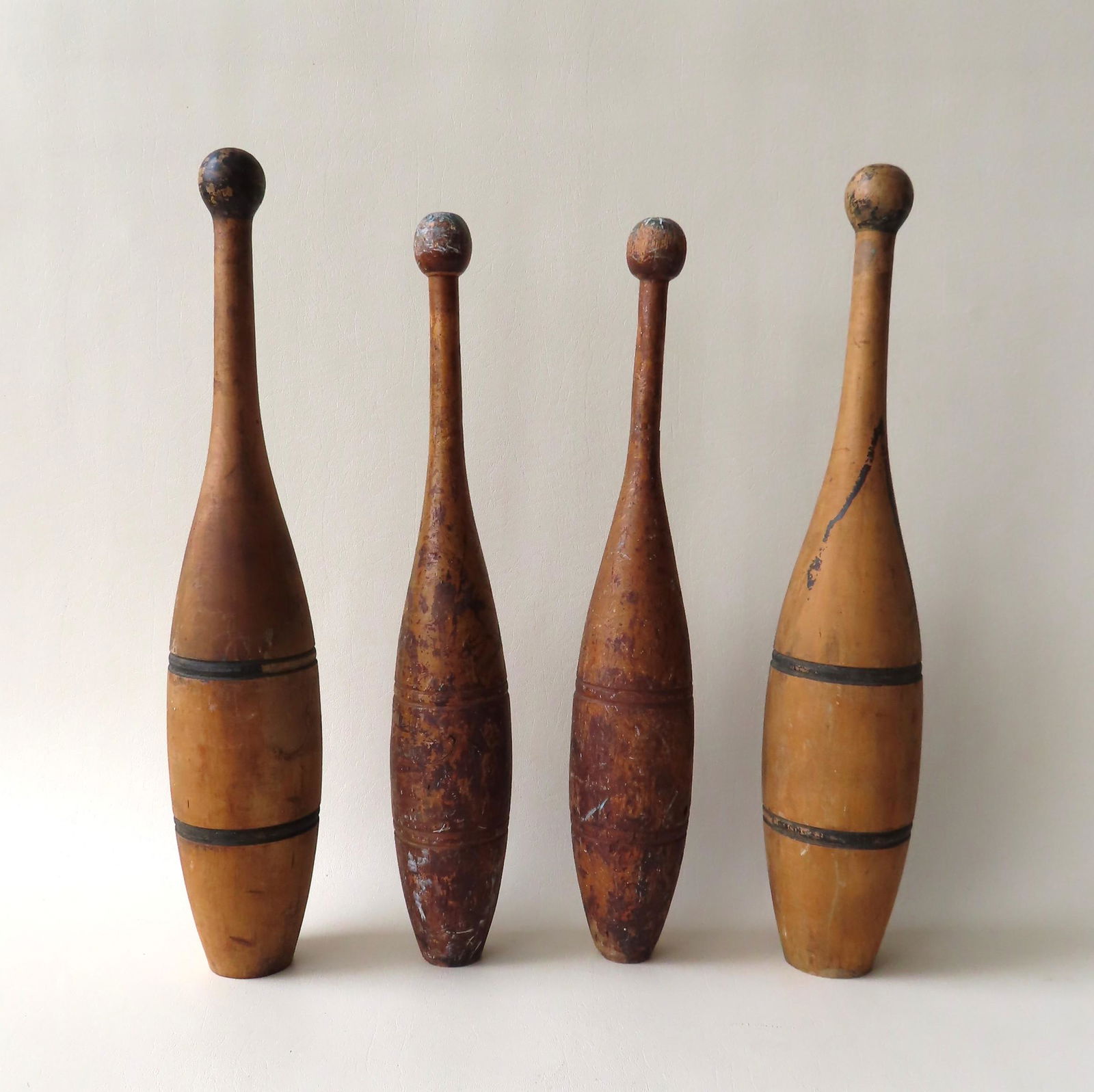 Two pair of wooden dumb bells, late 19th century: The: Two pair of wooden dumb bells, late 19th century: The first pair with traces of original mustard paint - 18 1/2"H - extensive use wear including 2 small wood splits at base of neck (see photos); and t