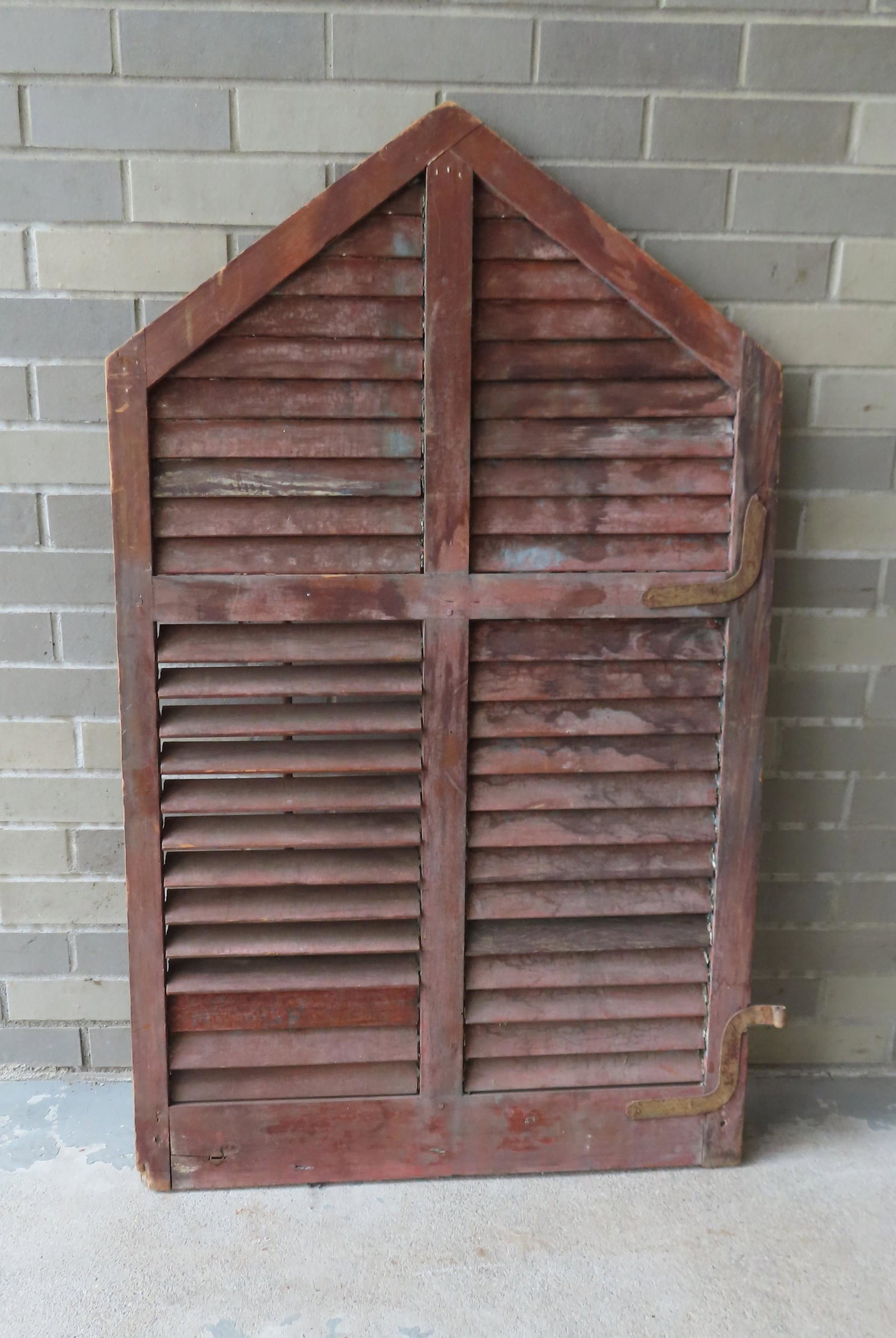 A gothic style louvered shutter, mid 19th century in: A gothic style louvered shutter, mid 19th century in old green/blue paint. One of the hinges is missing, one louver loose, else good condition.