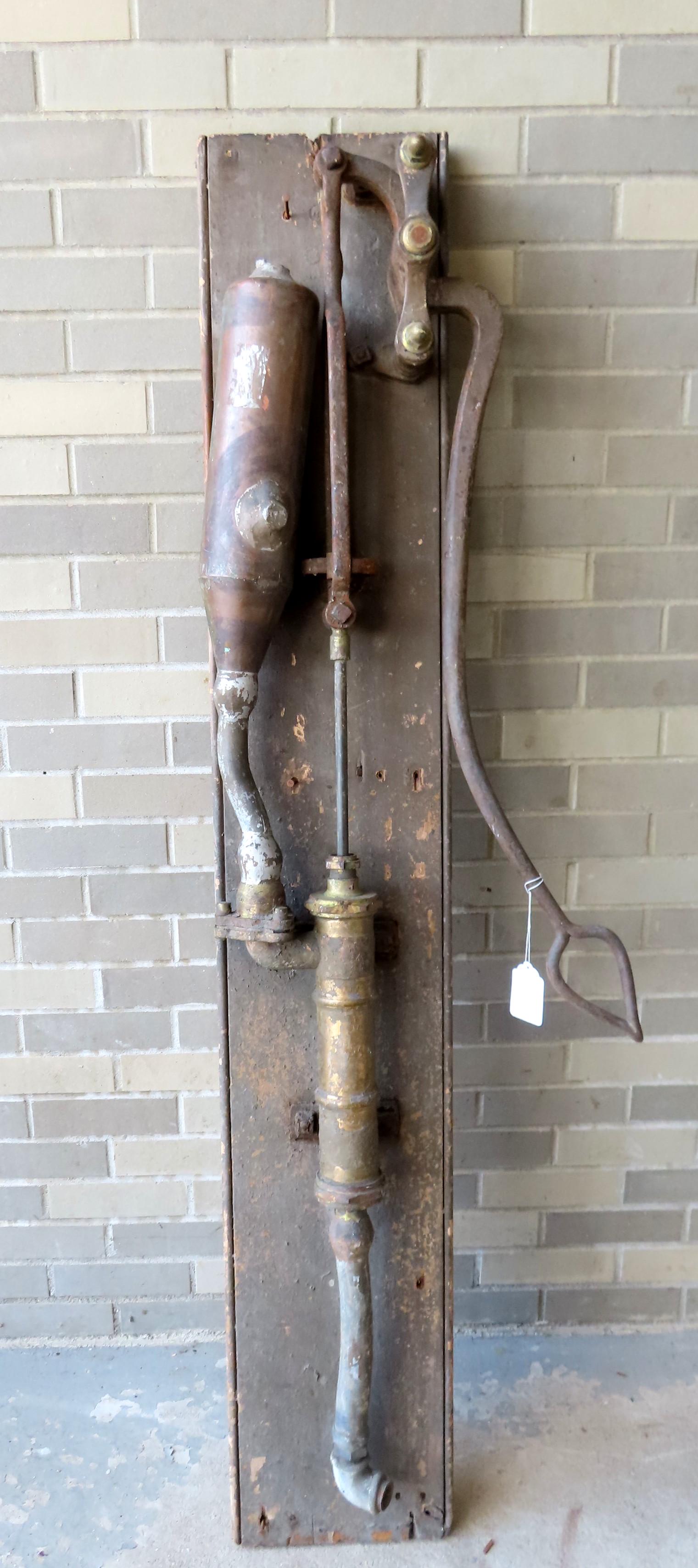 An unusual water pump mounted on wooden plank: An unusual water pump with long cast iron handle mounted on a wooden plank. The arm and pump move properly but terminal parts missing - layers of old paint - burn mark on back of plank. Probably late 