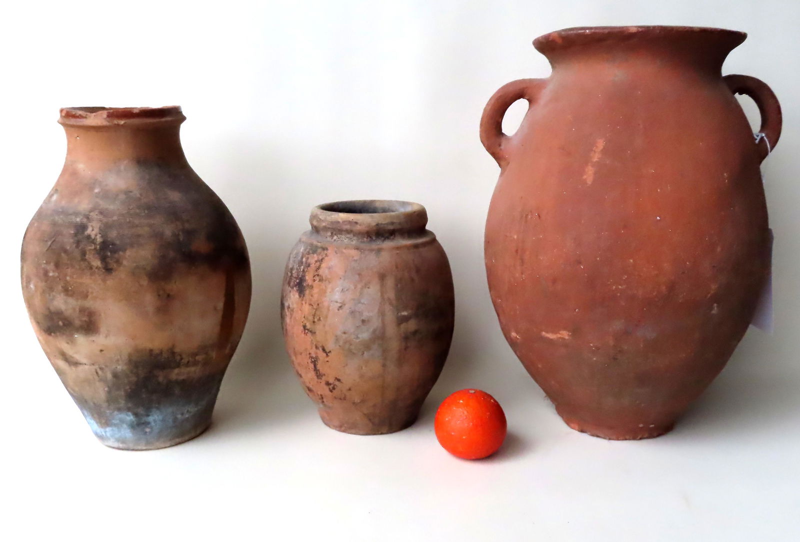 Three redware jars, the largest with double handles -: Three redware jars, the largest with double handles - approximately 17 1/4"H x 12"W - several chips along the edge of the flared rim and many small chips along the edge of the footed base - 19th centu