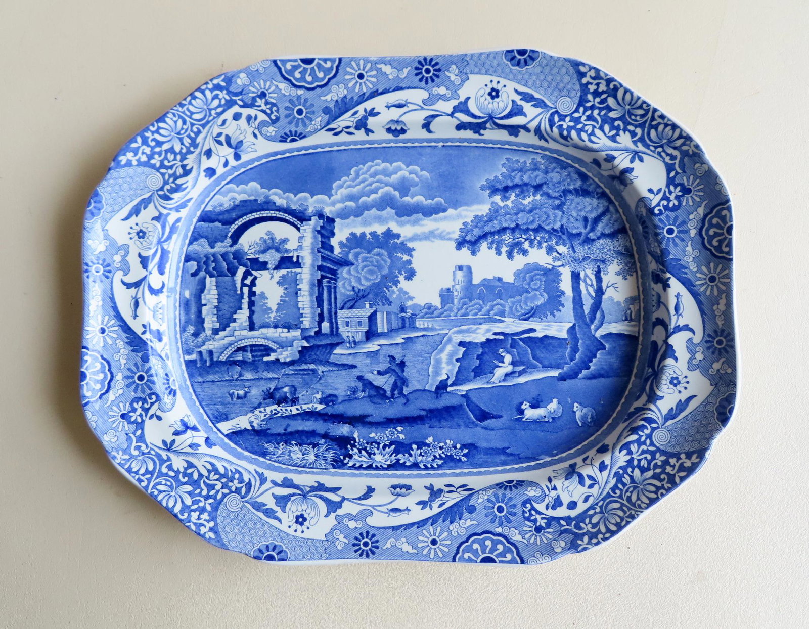 Blue and White Spode transferware platter.: A very fine blue and white Spode transferware platter depicting a country scene with castles, farmhouse, and shepherd with farm animals near stream and having a shaped floral border. Marked "Copeland 
