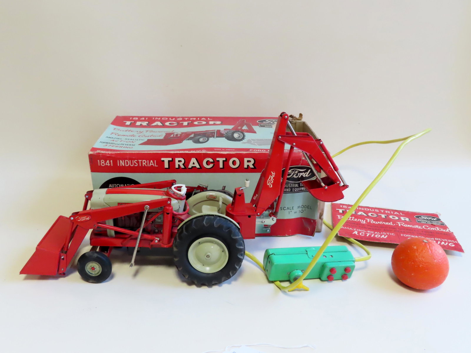 Battery operated toy tractor in original box.: Scale model, remote controlled, battery operated toy tractor in original box. The tractor marked "Ford 1841 Industrial", has a front loaded and backhoe attachment. The box marked "Ford Motor Company".