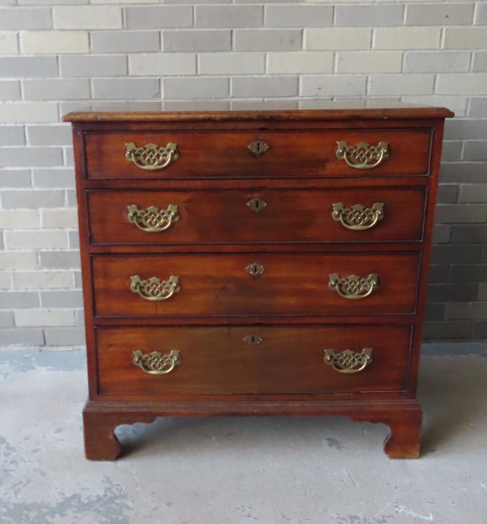 Chippendale chest on original bracket base having 4: Chippendale chest on original bracket base having 4 graduated drawers and top with molded edge, 18th century, probably English. Brasses appear to be 19th century replacements. Some surface abrasions, 