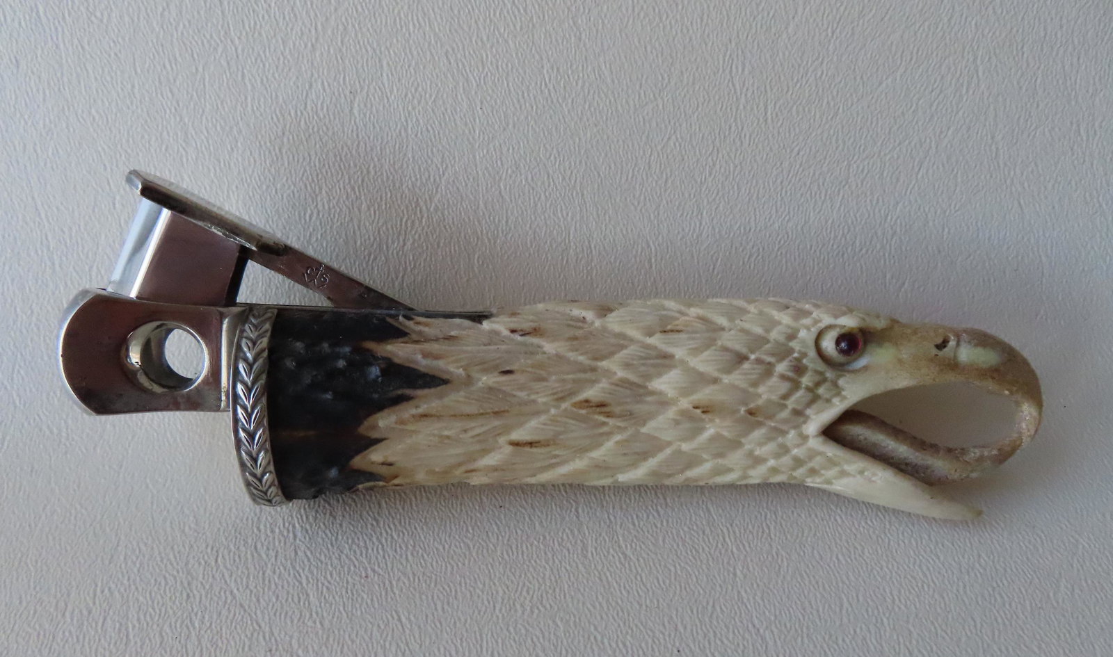 A cigar cutter in the form of a very finely carved bone: A cigar cutter in the form of a very finely carved bone eagle head with glass eyes, mid 20th century, very good condition - measures 6 1/8"L x 2 1/4"W.