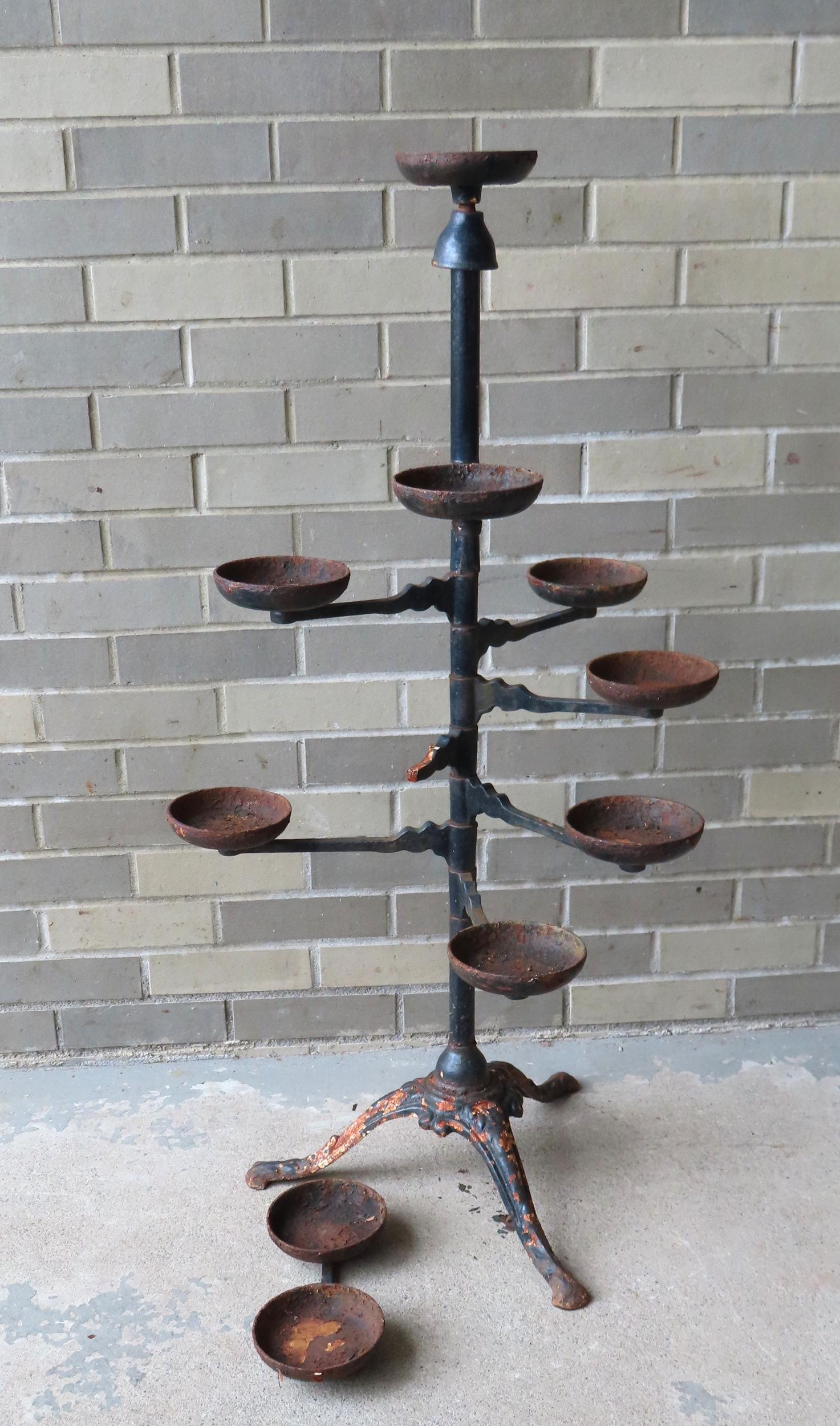 A cast iron floor standing plant holder with 9 arms with disks for holding plants. One arm with a (1 of 3)