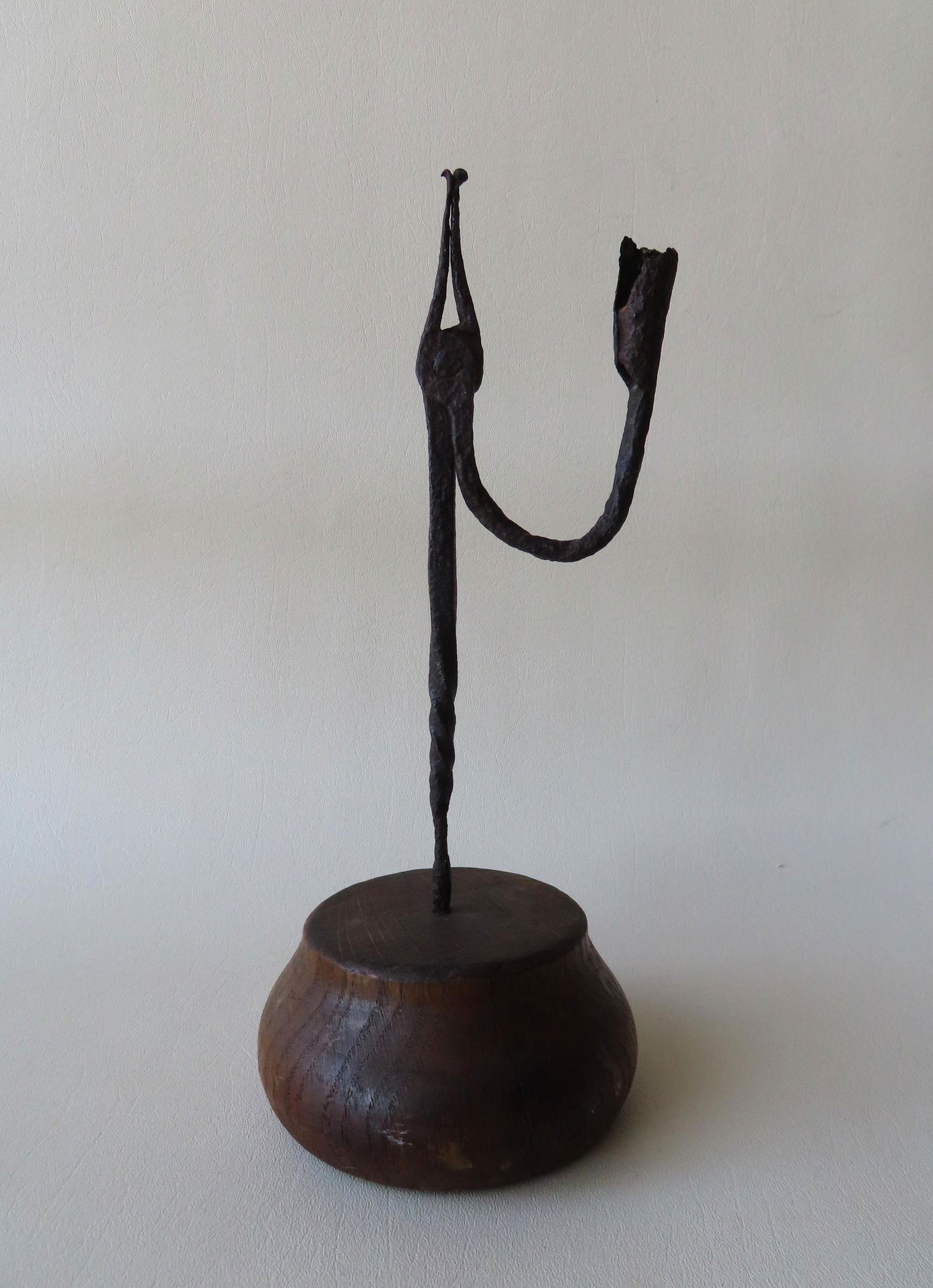 A hand forged iron rush light mounted on a circular wooden base. Some pitting, but good structural (1 of 3)