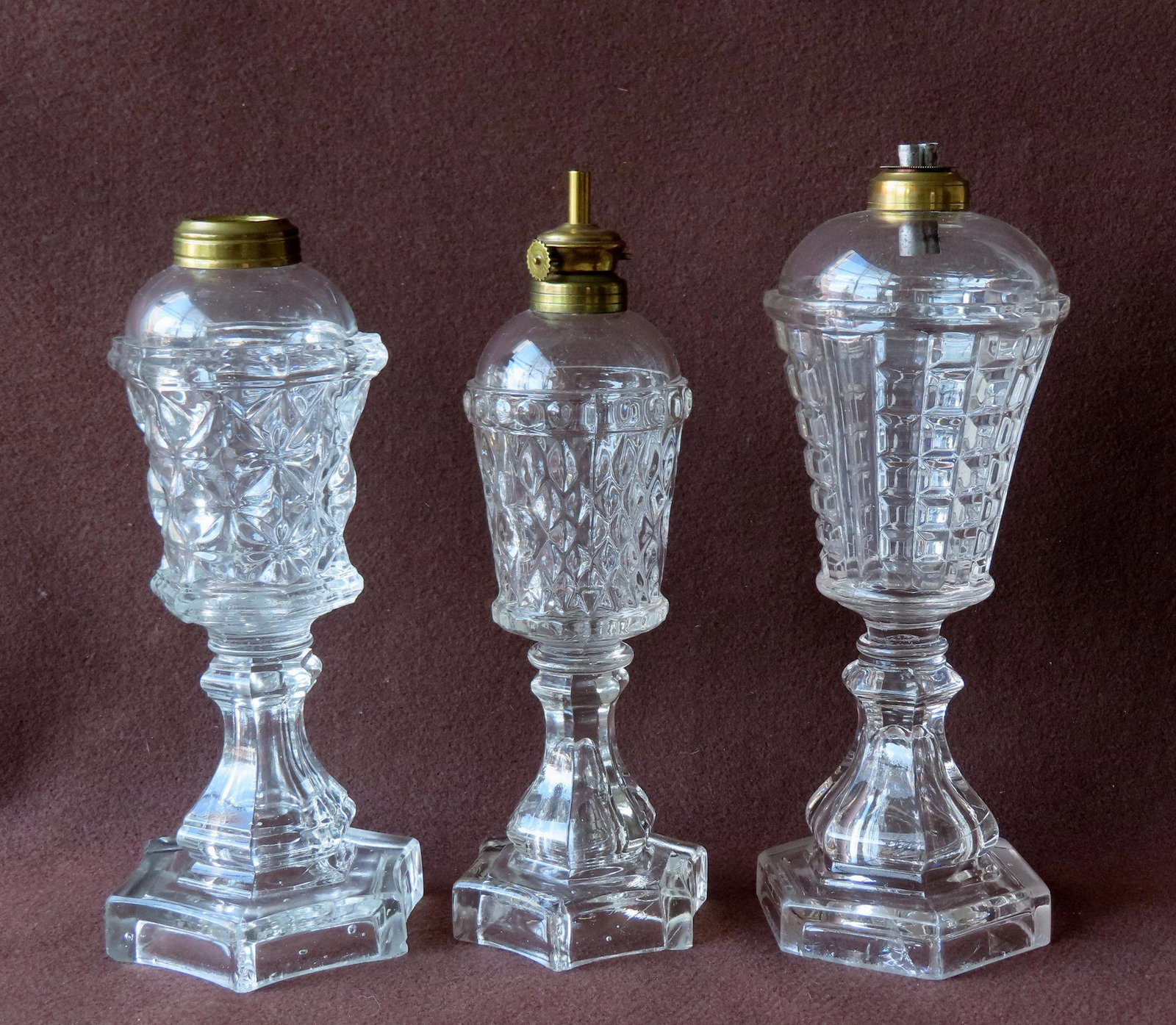 Three early whale oil lamps mounted on octagonal base and each having the typical glass wafer: Three early whale oil lamps mounted on octagonal base and each having the typical glass wafer attaching the oil font to the base. The largest 11 5/8"H. All in very good condition. Provenance: From the