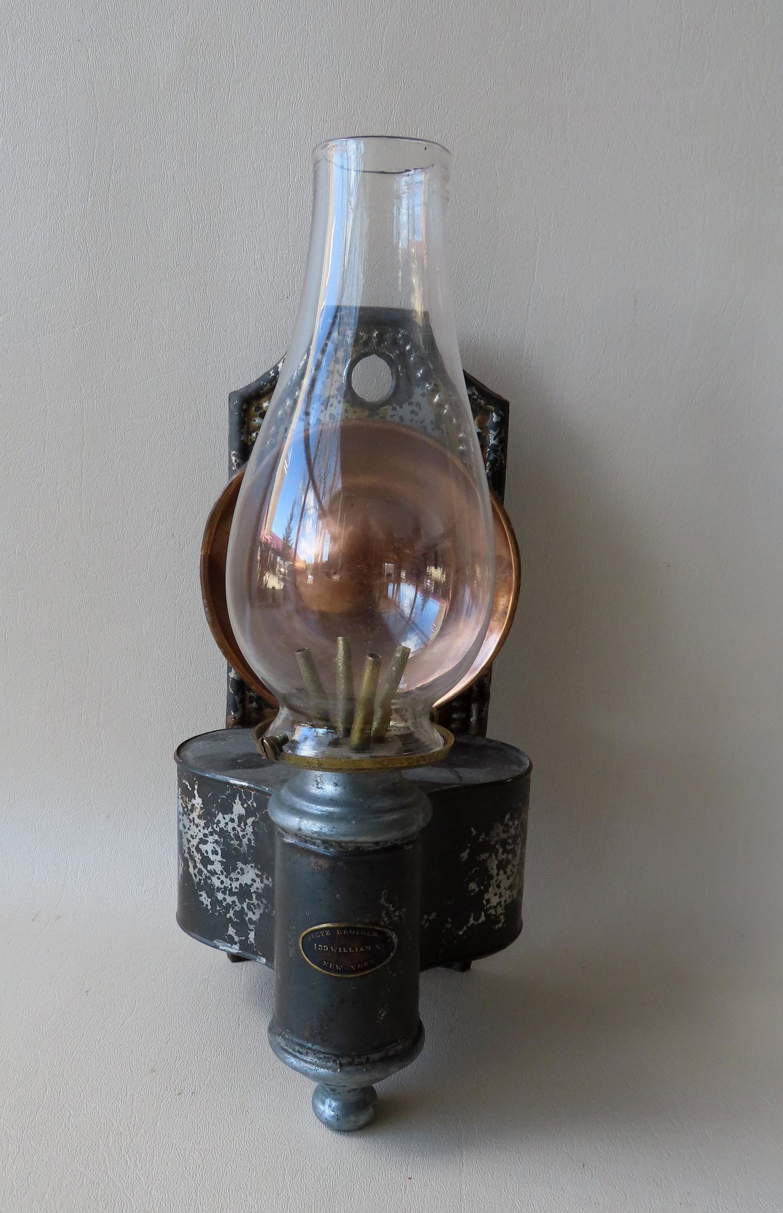 A tin wall mount whale oil lamp with brass reflector, trace of original paint, signed "Deitz Brother: A tin wall mount whale oil lamp with brass reflector, trace of original paint, signed "Deitz Brother & Co. / 139 William St. / New - York", circa 1845. Note - Deitz & Brother started producing sperm o