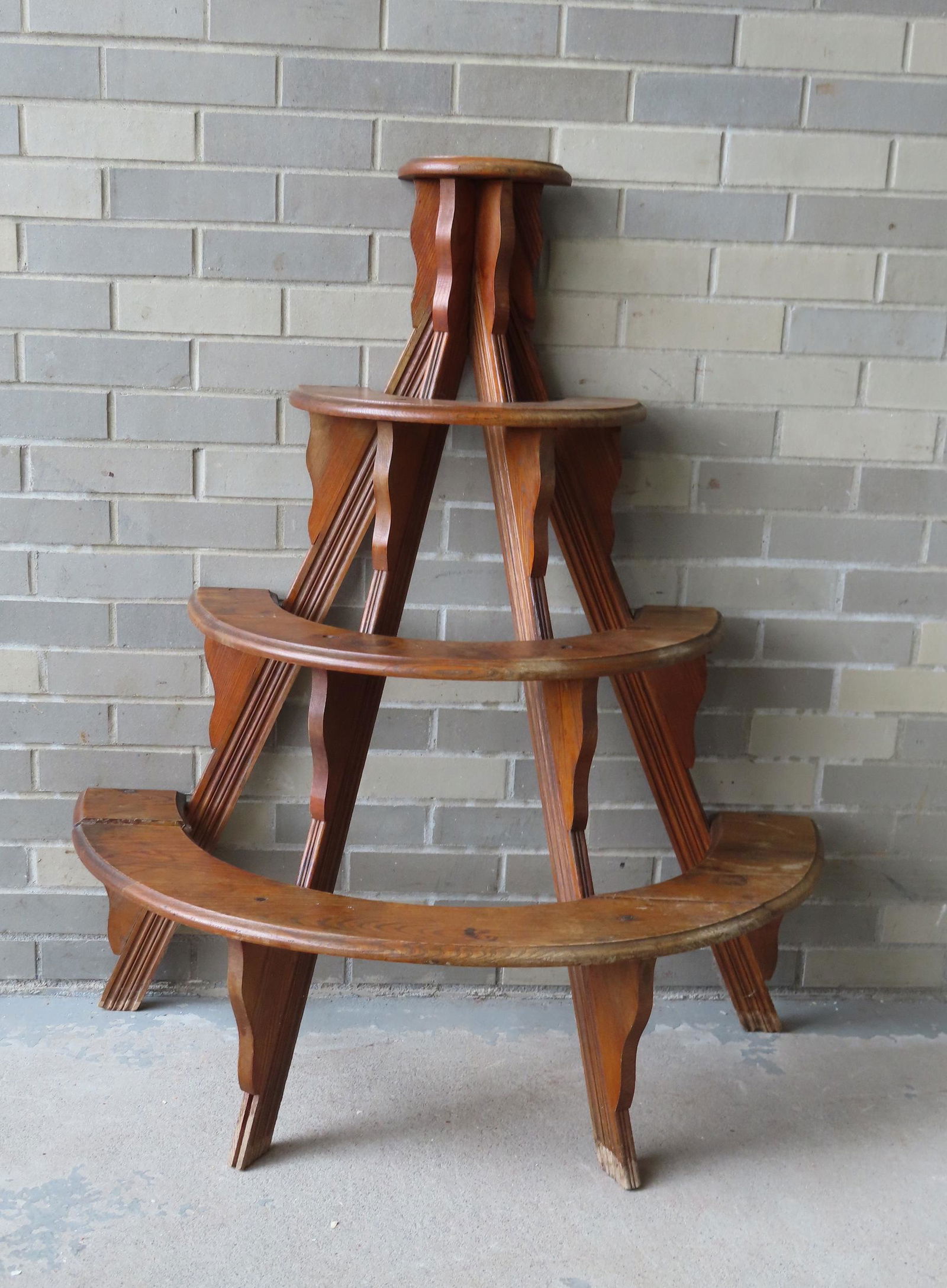 A half round wooden plant stand with 4 tiers and natural finish. The 2 lower tiers with several (1 of 4)