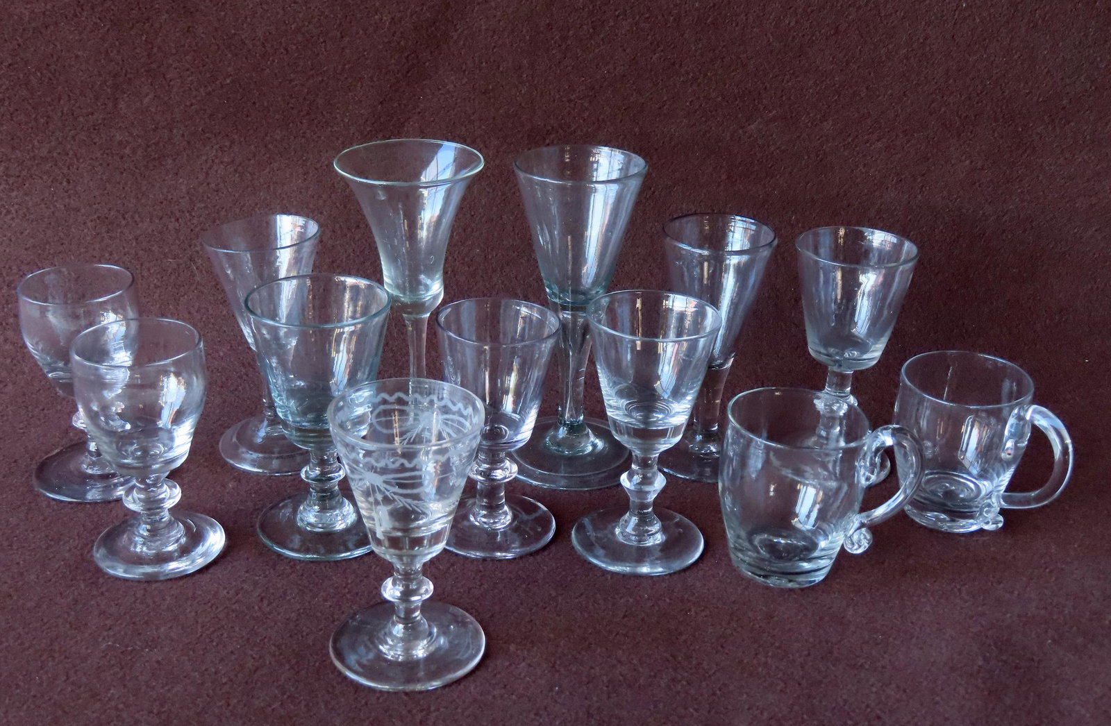 Assorted grouping of 13 hand blown wine glasses and 2 cups with applied handles - all with scarred: Assorted grouping of 13 hand blown wine glasses and 2 cups with applied handles - all with scarred pontils. The largest 5 1/2"H x 2 3/4" diameter. Includes one etched cordial decorated with ribbons, t
