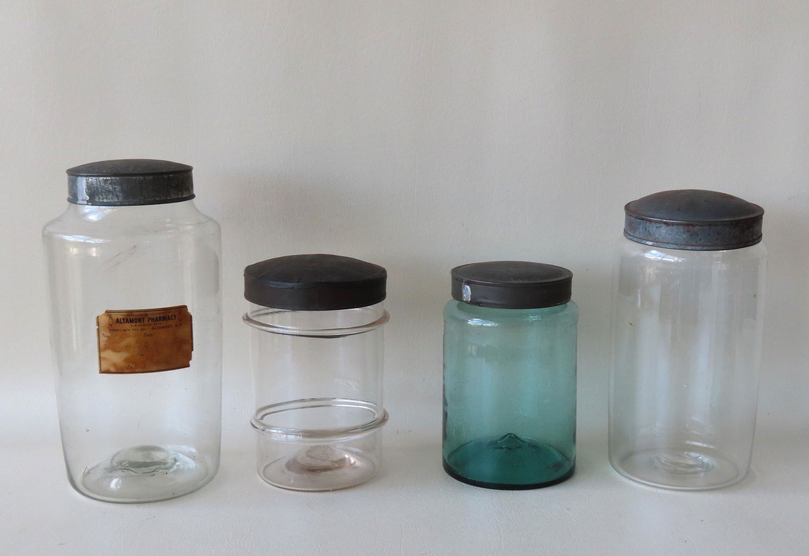Four hand blown apothecary jars with tin lids and open pontil scars, 19th century. Ranging in size (1 of 16)