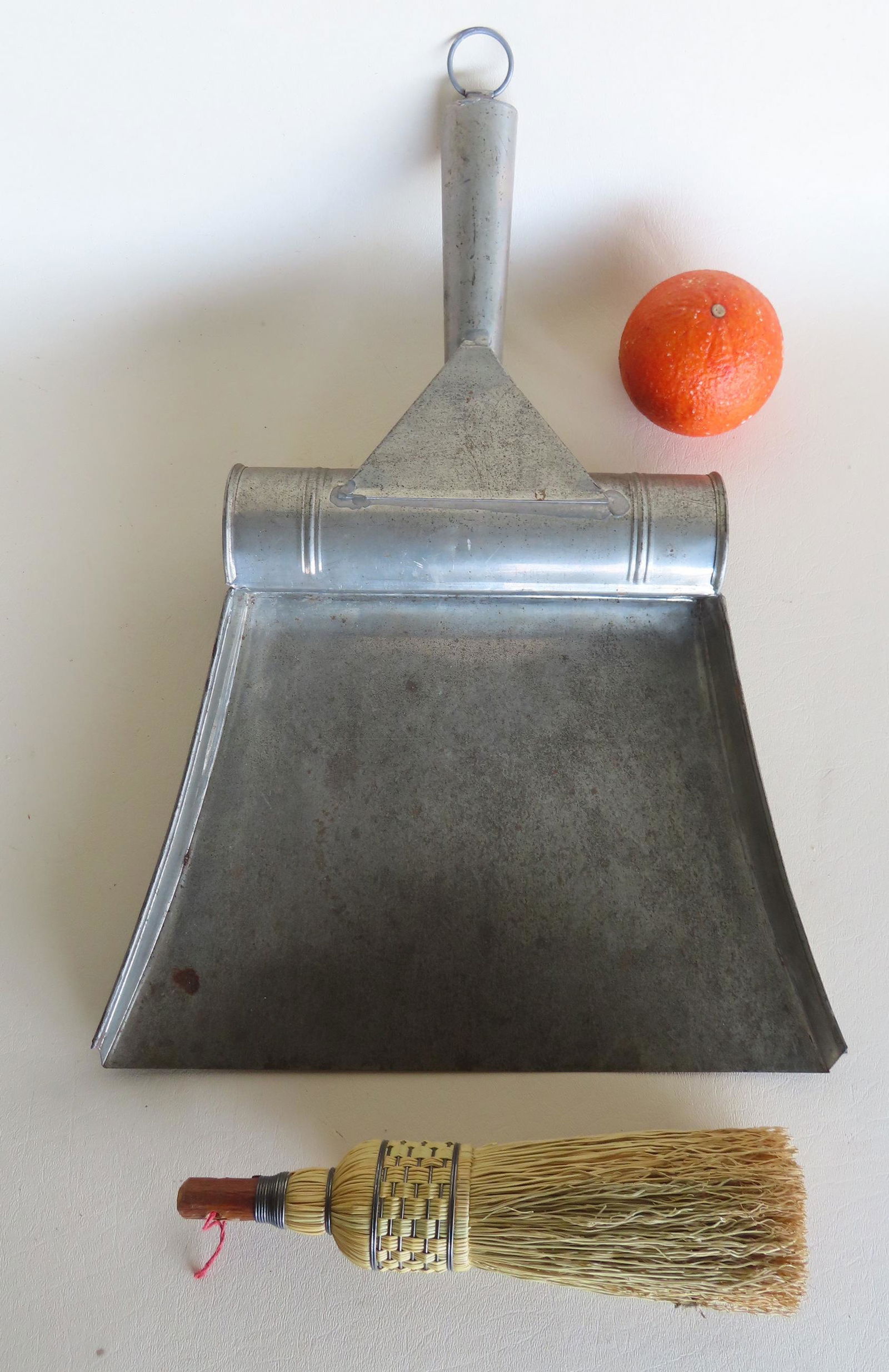 A tin dust pan with a hand made brush that is stored within an open cylinder in the handle. Very (1 of 6)