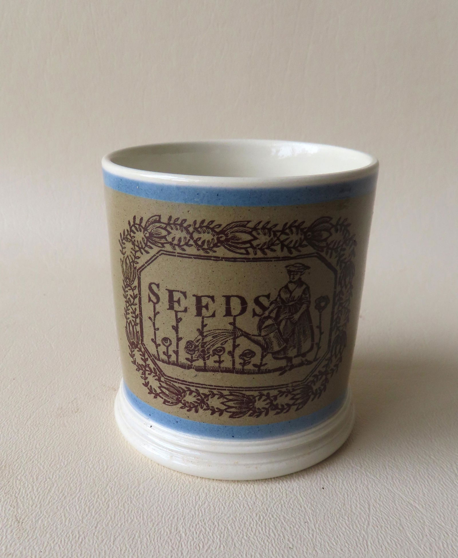 A small mochaware seed cup having blue bands across the top and above the footed base. The front (1 of 5)