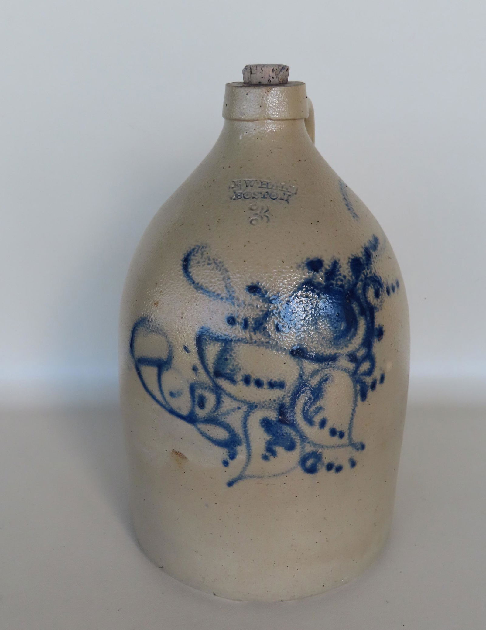 A stoneware jug, 3 gallon, decorated with a large blue flower, with the impressed mark of "E.W. HALE (1 of 5)