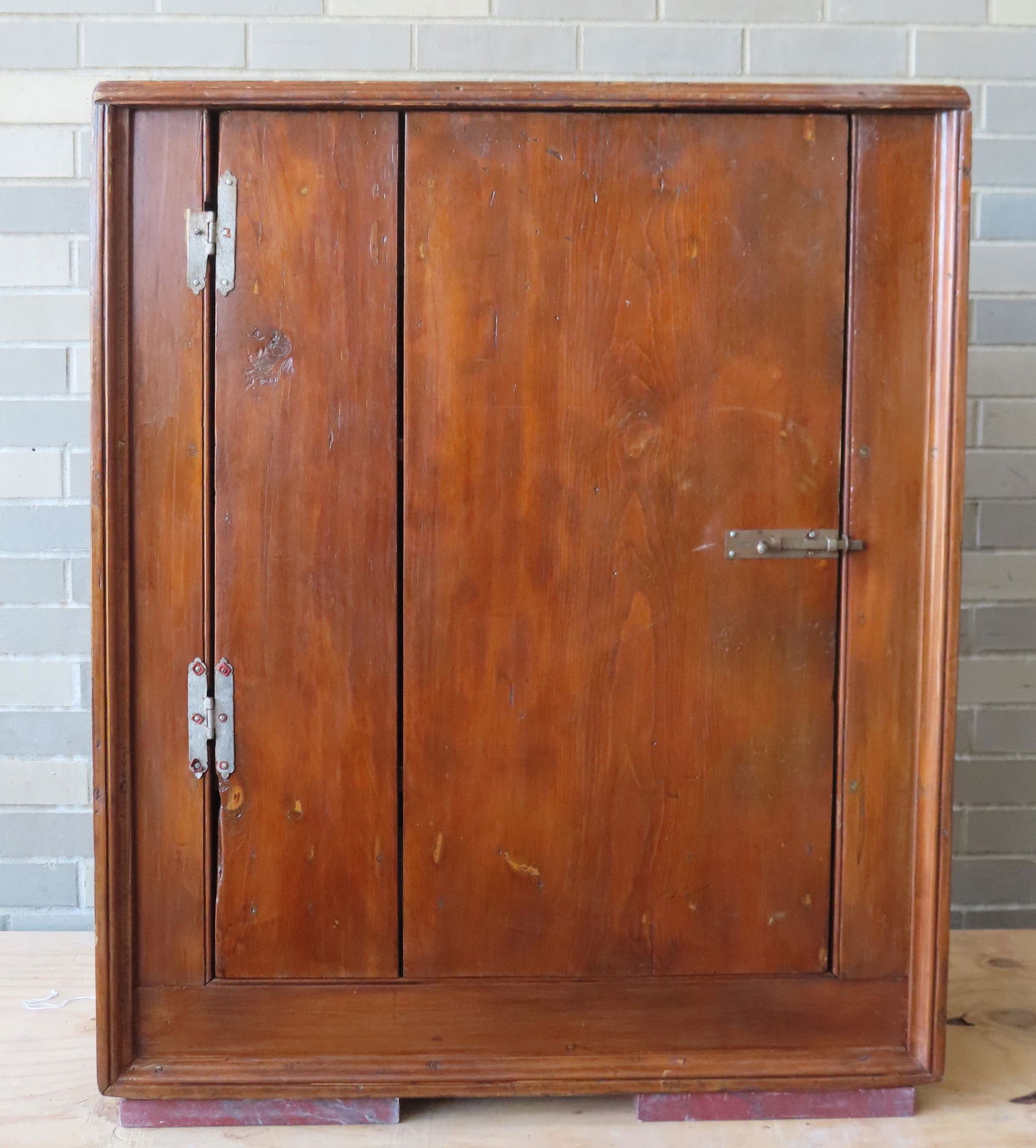 A small primitive 1 door floor cupboard with picture frame molding, circa 1800. Stands uneven due to (1 of 5)