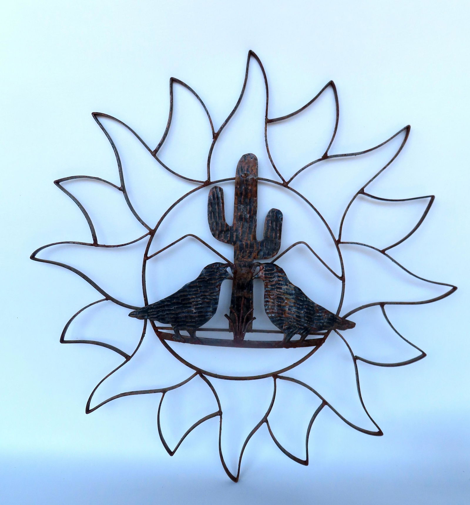A decorative metal wall sculpture depicting 2 birds standing in front of a cactus plant surround by (1 of 3)