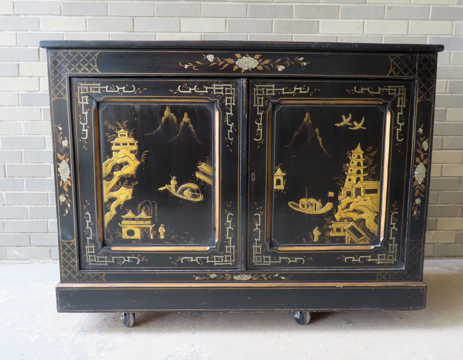 An ebonized and hand painted 2 part Chinoisere china cabinet. The sides with relief carvings of (1 of 20)
