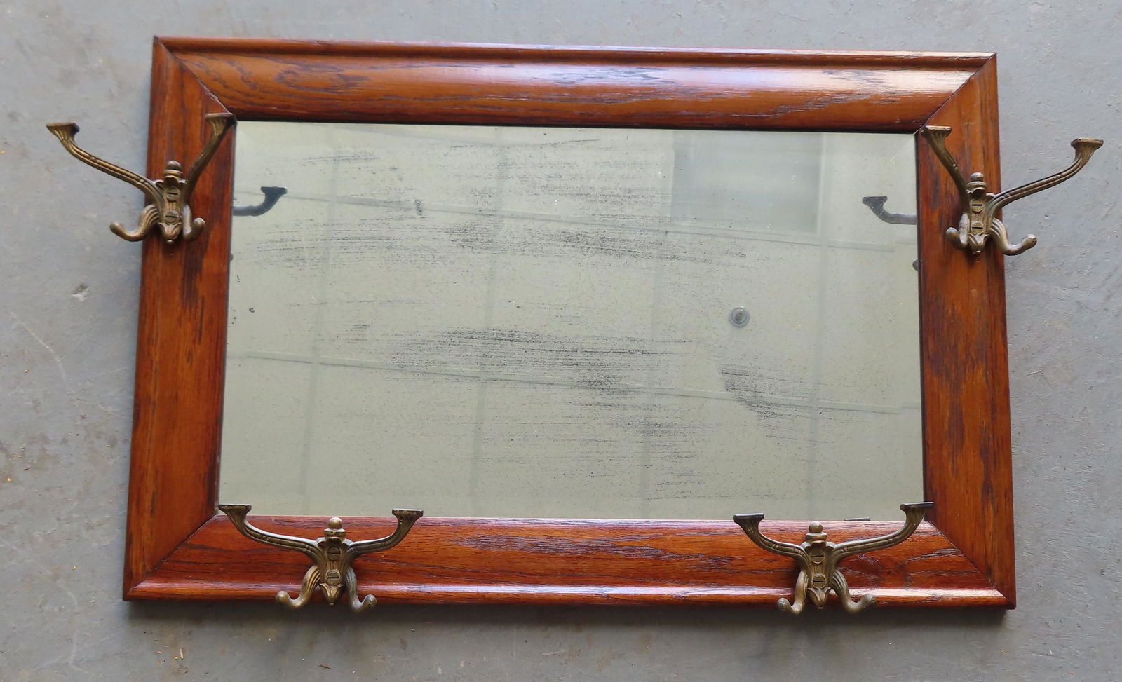 An oak beveled glass wall mirror with attached hat hooks in each corner, late 19th to early 20th (1 of 3)