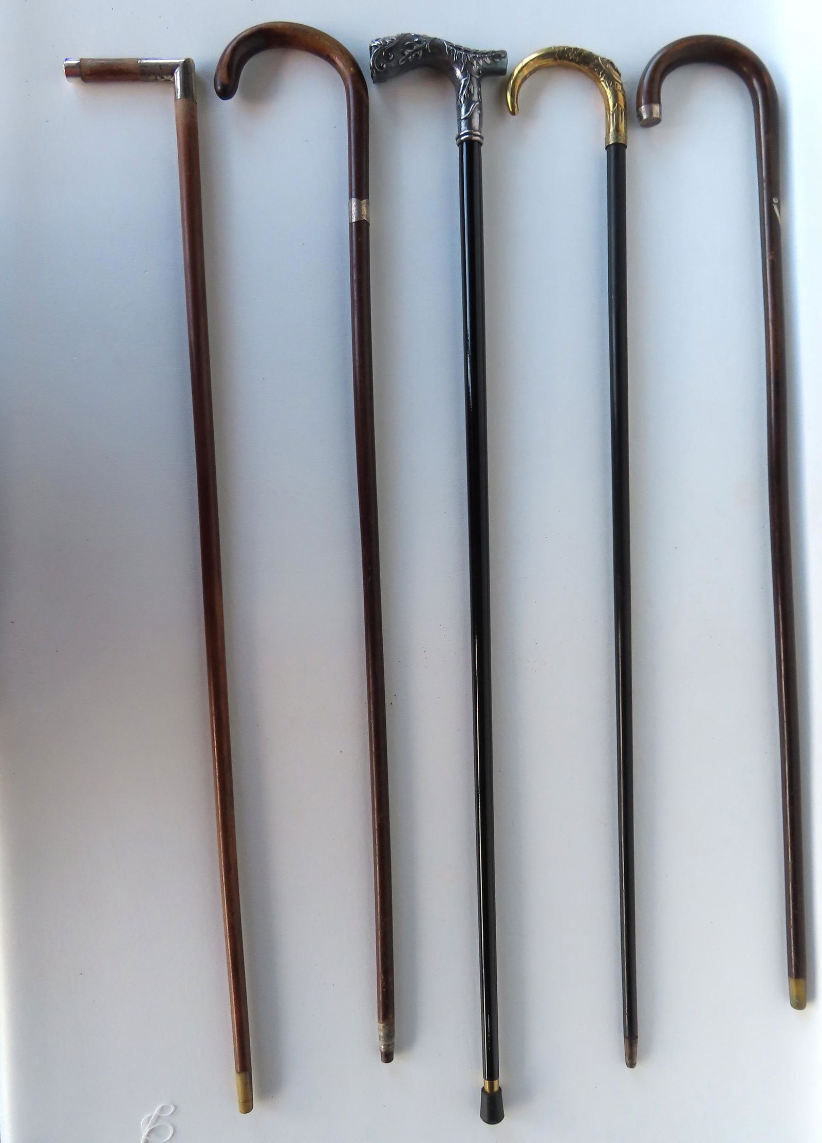 Grouping of 5 walking sticks including: Gold plated with embossed acanthus leaves and gothic face (1 of 4)