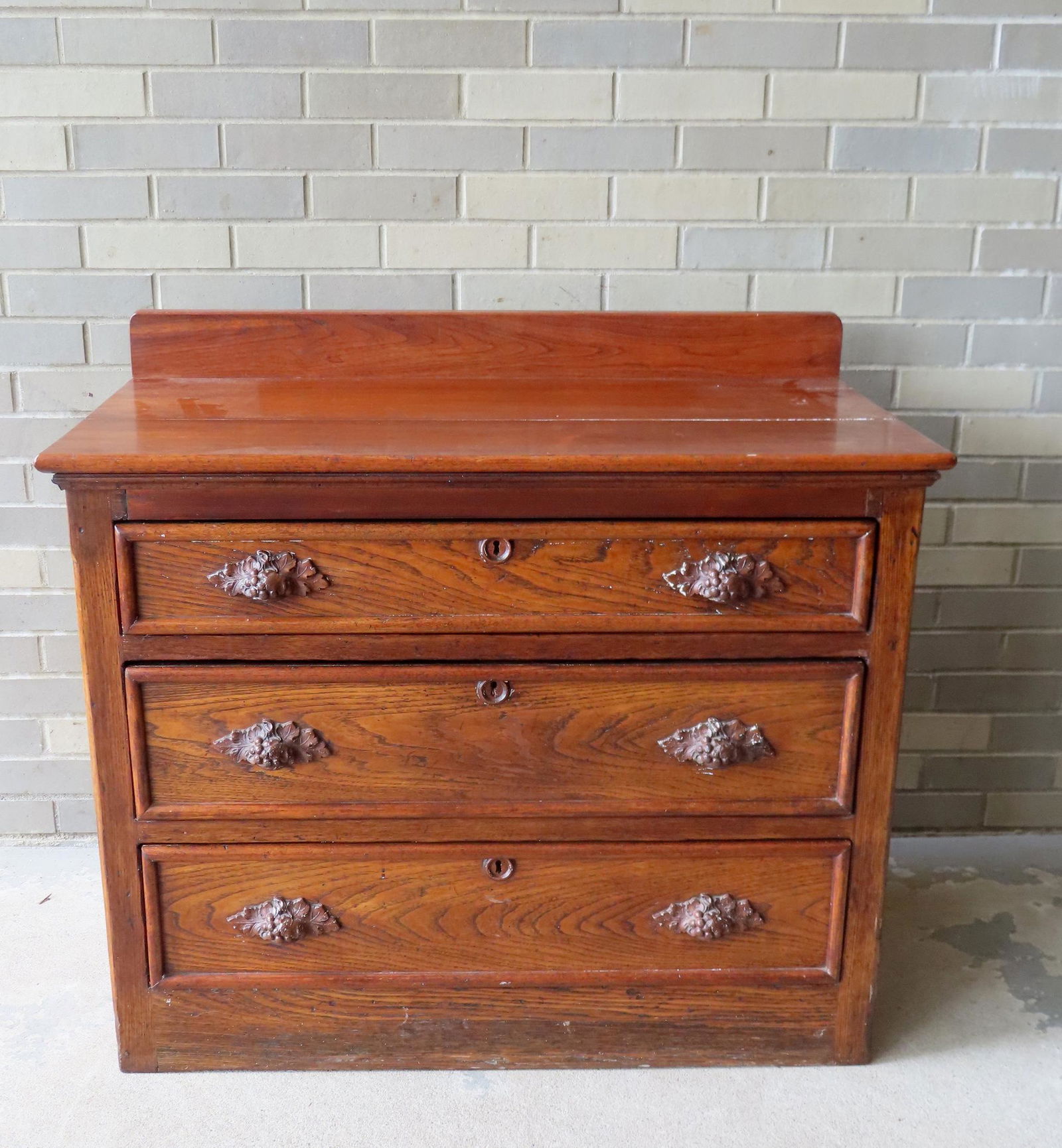A Victorian chest with 3 graduated drawers with carved pulls and backsplash, constructed with walnut (1 of 9)