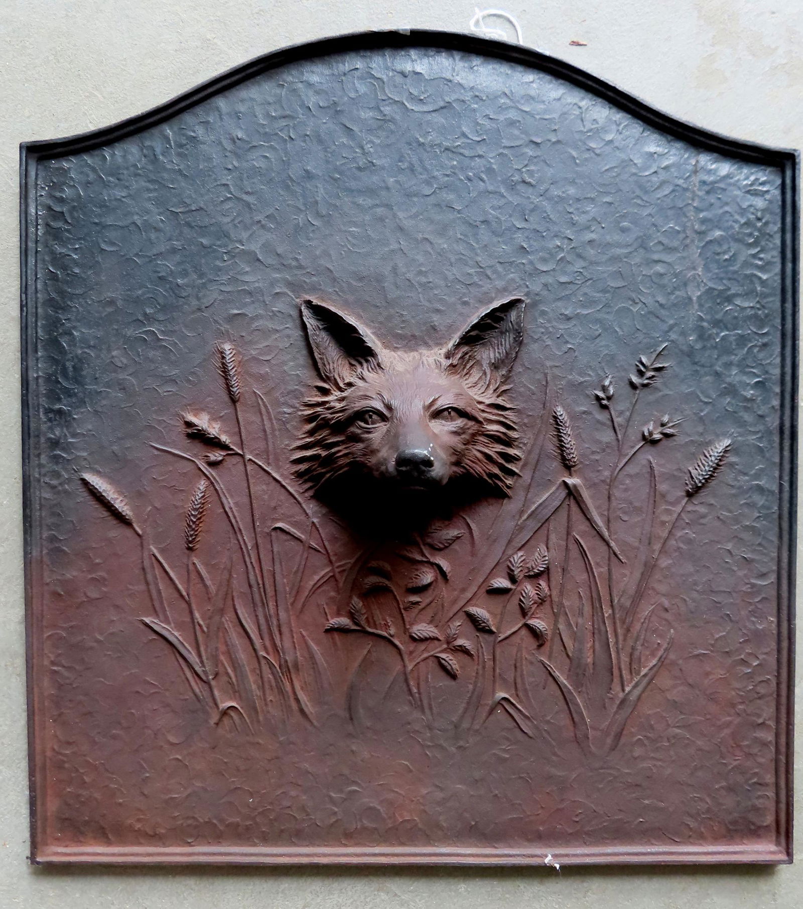 A cast iron fireback with arched top depicting a foxhead protruding from the center within field of (1 of 5)