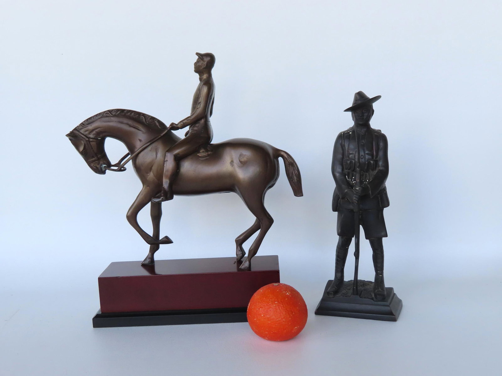 Two modern bronze sculptures including: 1) A jockey seated on race horse mounted on composition or: Two modern bronze sculptures including: 1) A jockey seated on race horse mounted on composition or wooden base - late 20th century - 12 1/2"W x 5"D x 14 1/2"H; 2) A standing WWI soldier in uniform hol