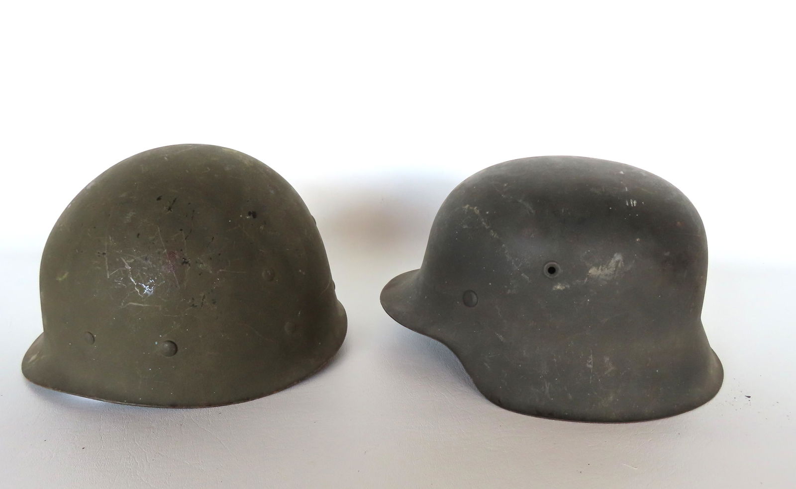 Two WWII helmets including US and German, both missing chin straps and the German missing lining, (1 of 7)