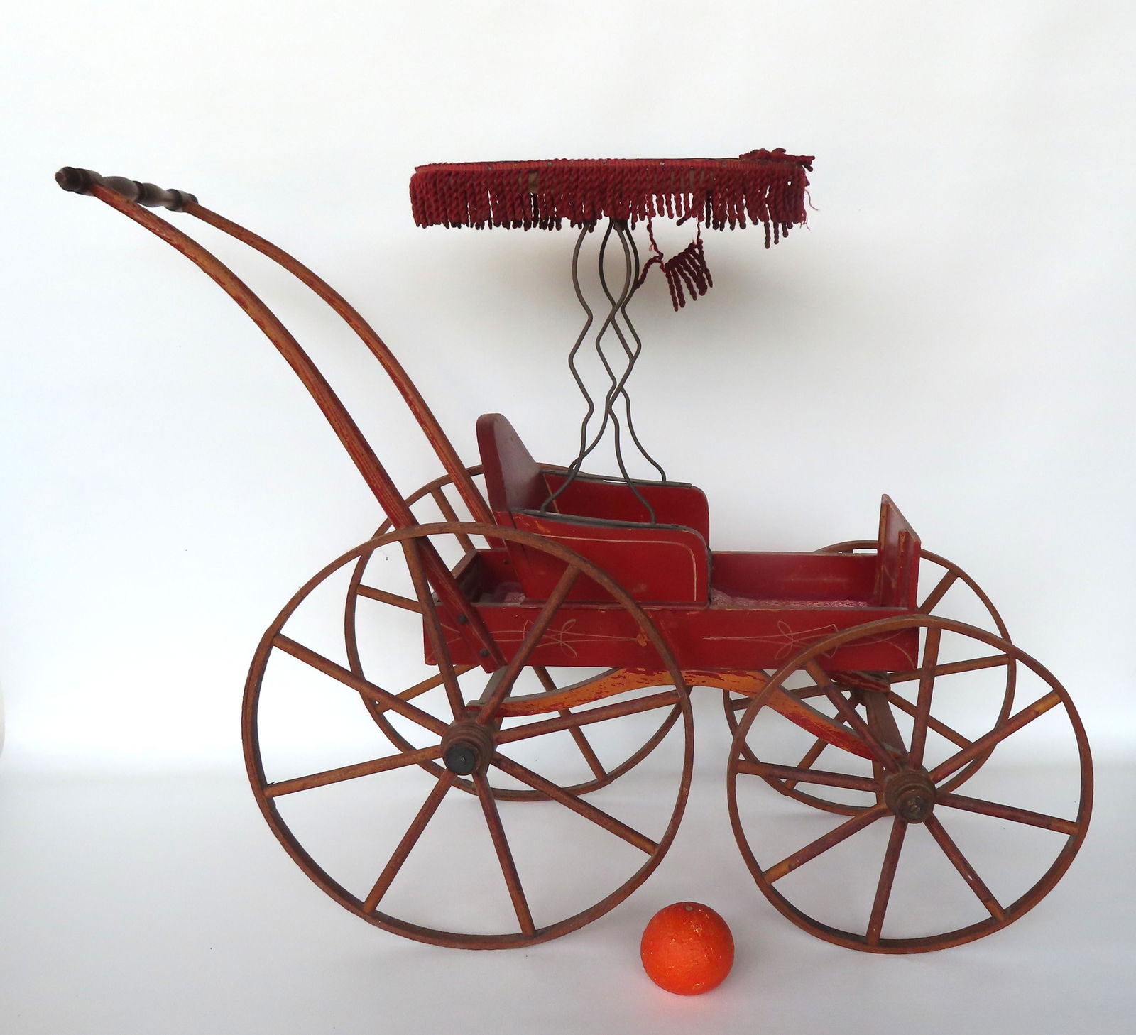 A 19th century doll carriage with canopy, wooden wheels, in original red paint with yellow pin (1 of 6)
