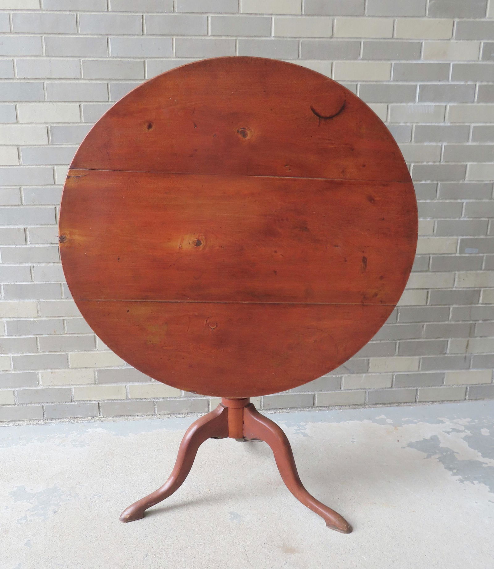 A refinished cherry Queen Ann tea table with bird cage, simple vase-form column leading to snake: A refinished cherry Queen Ann tea table with bird cage, simple vase-form column leading to snake feet with pads, 18th century, traces of original red stain. The top of 3 boards with slight separation,