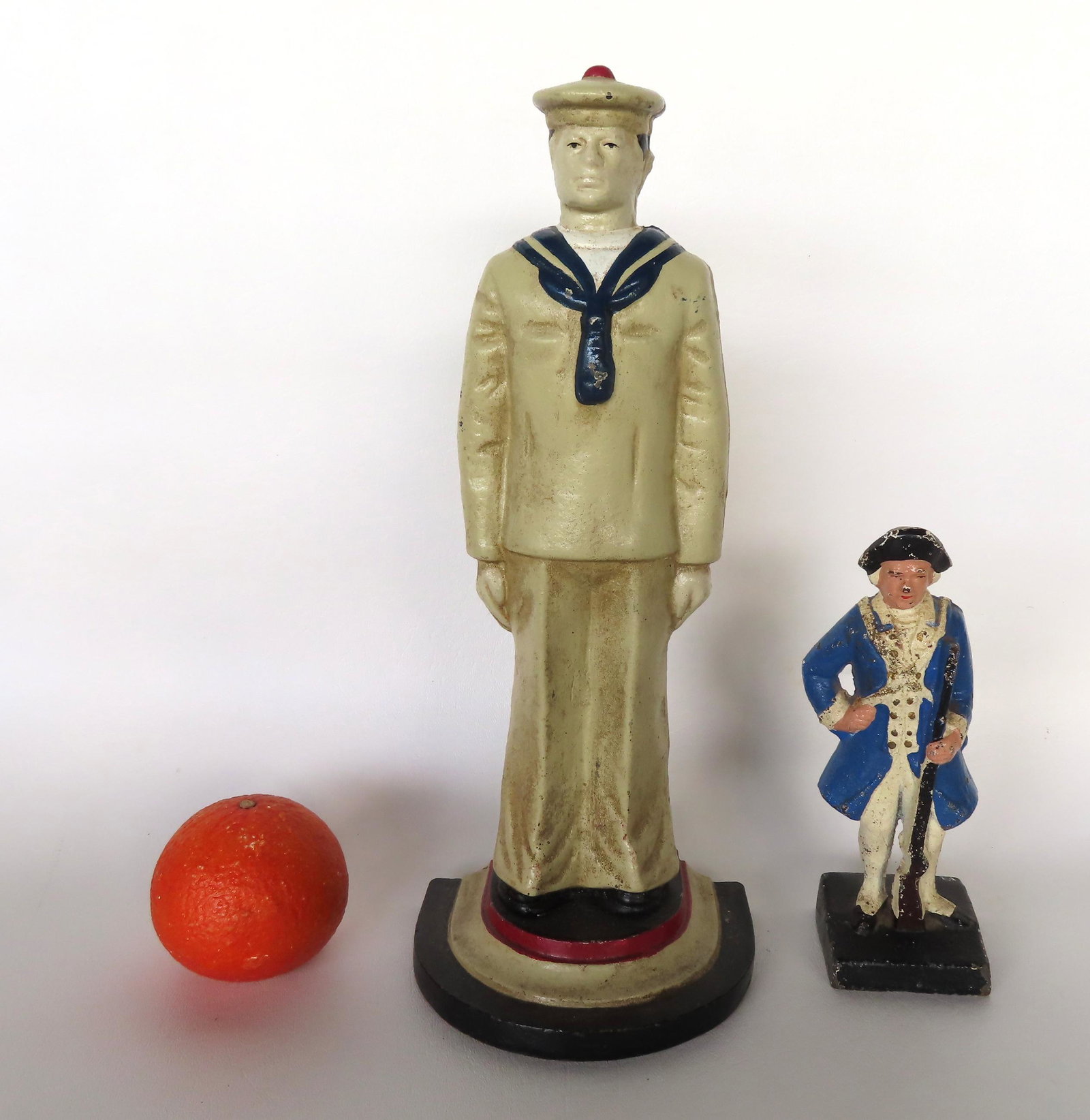 Two cast iron military men door stops. The first a standing sailor measuring 13 1/2"H - circa 1950;: Two cast iron military men door stops. The first a standing sailor measuring 13 1/2"H - circa 1950; and a Minute Man door stop with rifle measuring 7 1/2"H - both appear to be in original paint and in
