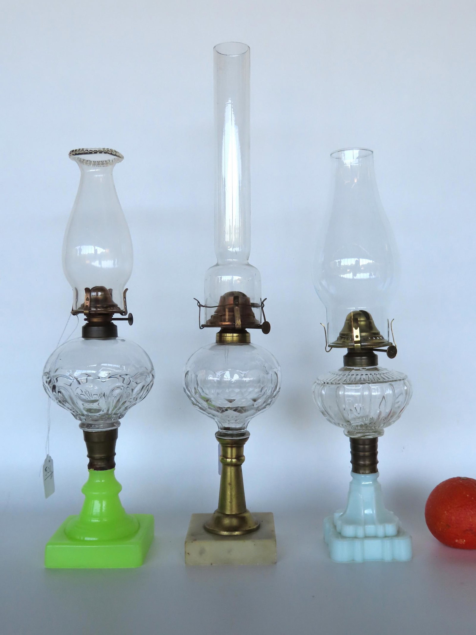 Three good classical oil lamp with glass fonts attached to brass collars attached to columns in: Three good classical oil lamp with glass fonts attached to brass collars attached to columns in vaseline, brass and milk glass, all in very good condition, 19th century The largest 10 3/4" H to top of