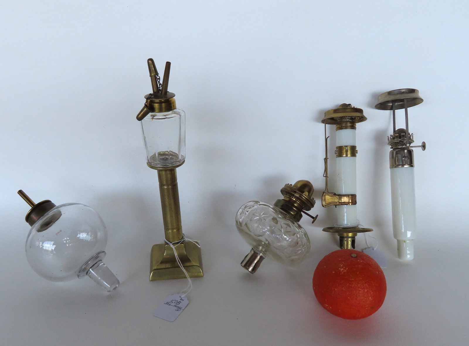 Grouping of 5 lighting devices including: 3 peg lamps - 1 hand blown with fluid burner (some: Grouping of 5 lighting devices including: 3 peg lamps - 1 hand blown with fluid burner (some imperfections in the glass), one cut with oil burner, and 1 blown with whale oil burner currently mounted i