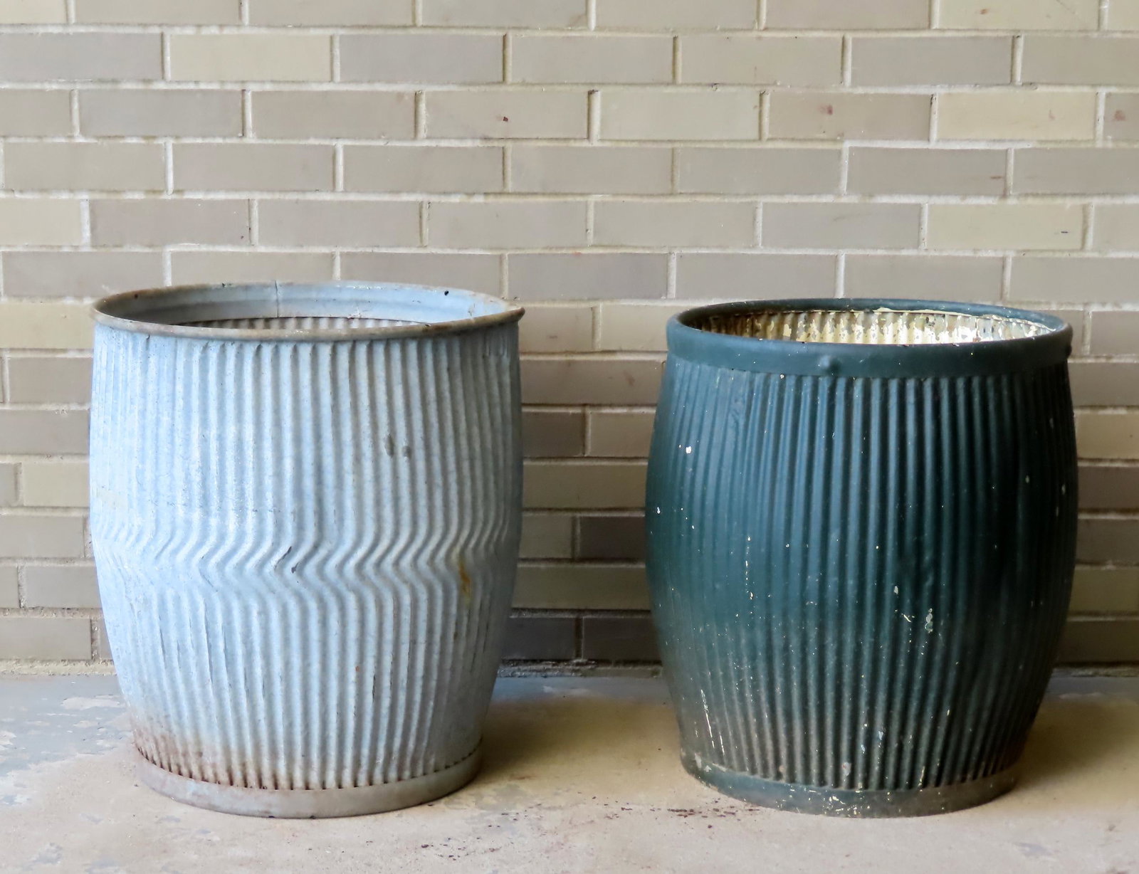 Two French galvanized metal water barrels with reeded design to sides, one in natural finish, the: Two French galvanized metal water barrels with reeded design to sides, one in natural finish, the other in old green paint, both late 19th to early 20th century. The largest measures 21" Dia. X 19"H. 