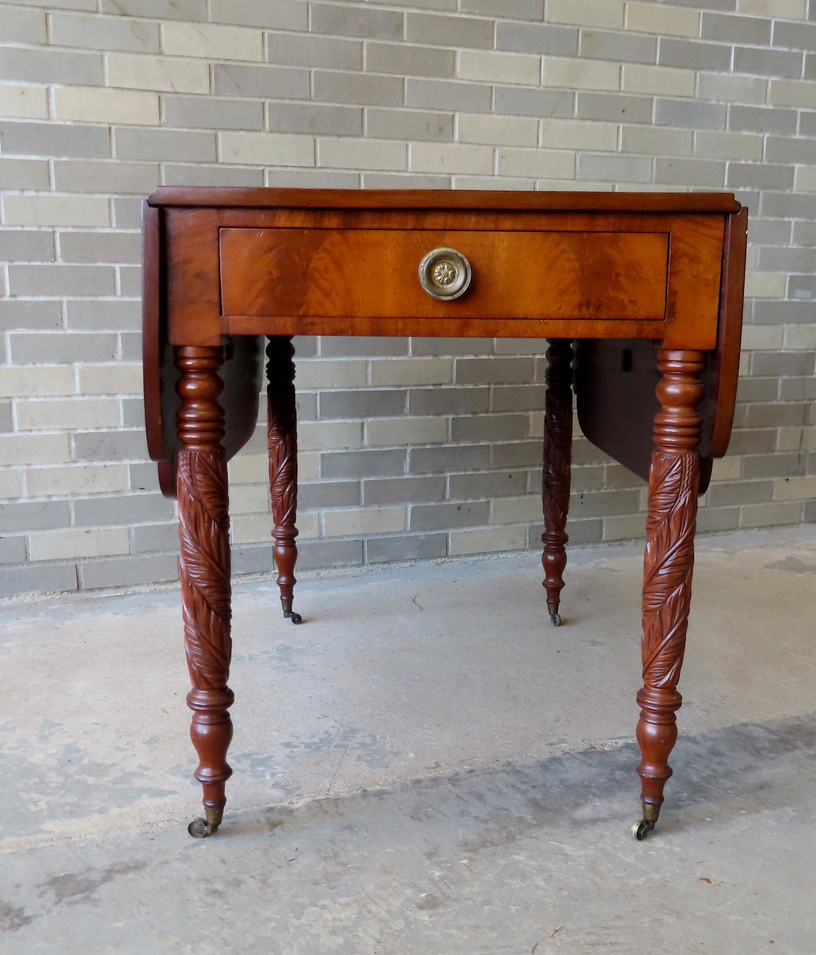 An outstanding Dutchess County NY mahogany drop-leaf table having shaped leaves, end drawer with: An outstanding Dutchess County NY mahogany drop-leaf table having shaped leaves, end drawer with original brass pull and having acanthus carved legs leading to original casters. Measures 24 1/4"W (lea