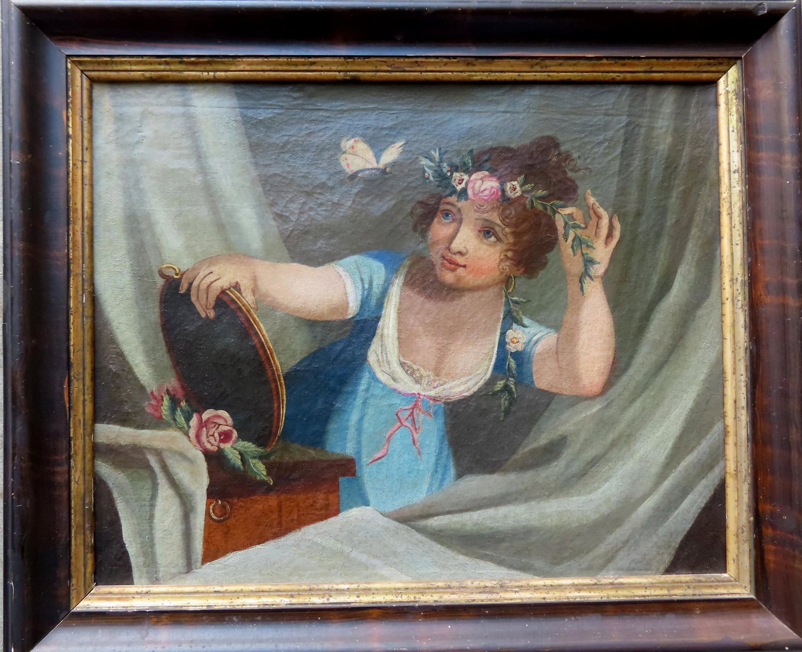 A folk portrait of a young lady holding flowers in one hand near flying butterfly and holds a mirror: A folk portrait of a young lady holding flowers in one hand near flying butterfly and holds a mirror in her other hand, circa 1870. Original grain painted frame with gold inset and having a hand made 