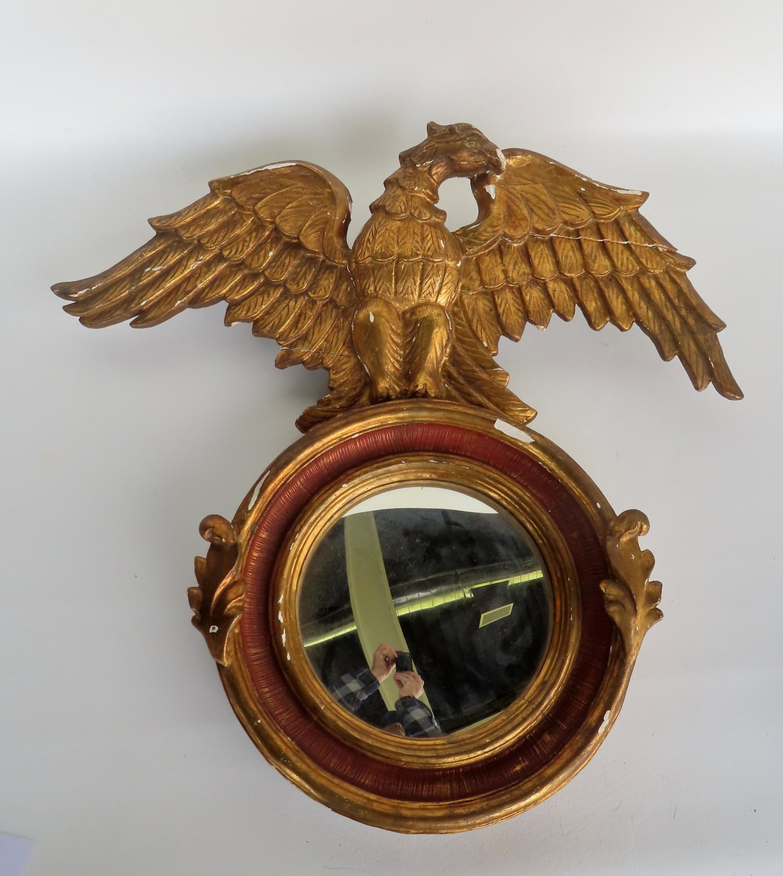 A gilt gesso bullseye mirror with red paint over gilt on mirror inset and having a crest of a large: A gilt gesso bullseye mirror with red paint over gilt on mirror inset and having a crest of a large carved spread wing eagle (gilt gesso over wood) - probably mid to late 19th century. Measures 28 1/2